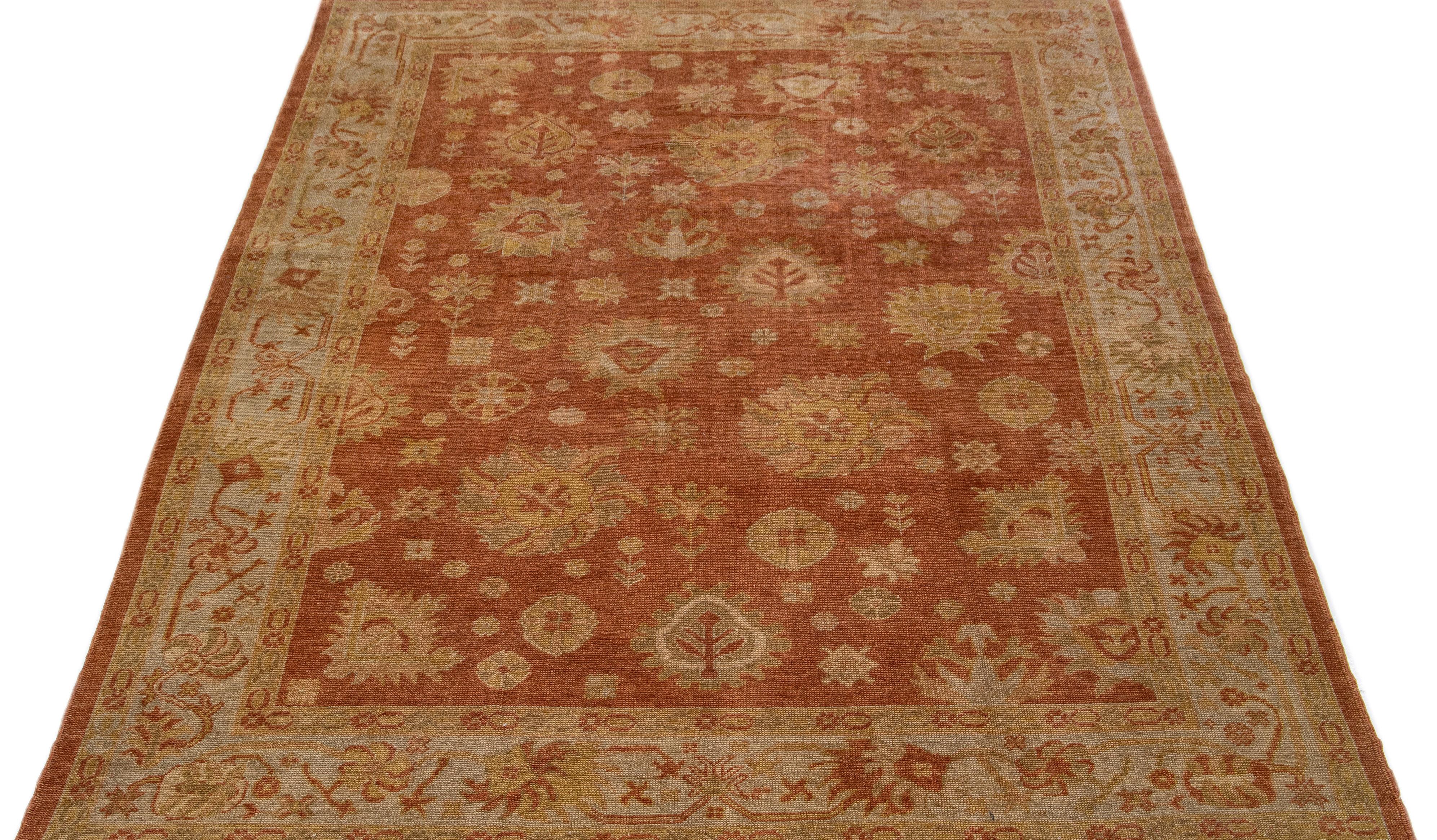 Magnifique tapis turc moderne en laine nouée à la main avec un champ de couleur brun-orange. Ce tapis présente un cadre gris avec des accents de vert et de jaune dans un magnifique motif floral géométrique sur toute la surface.

Ce tapis mesure :