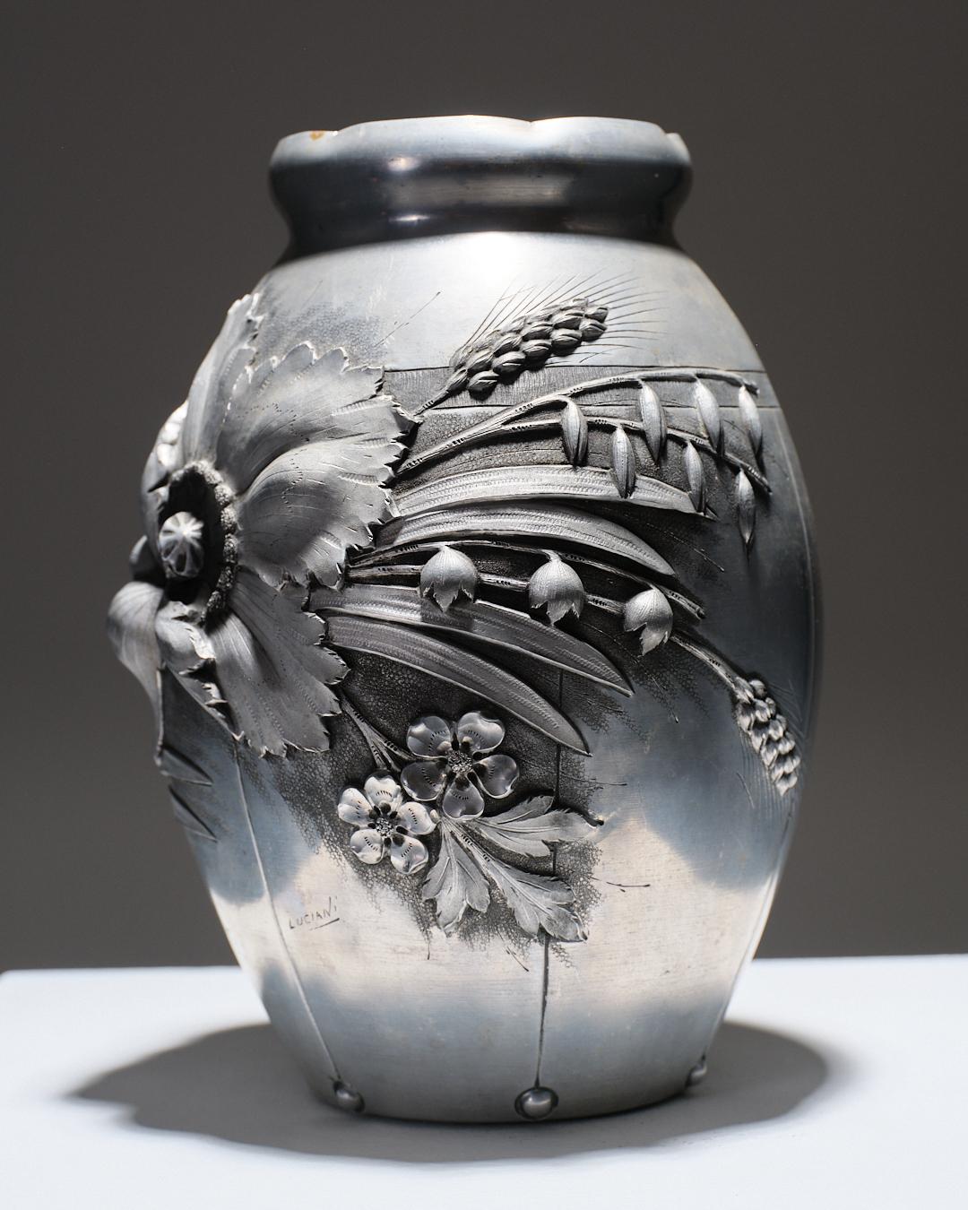 Vase Art Nouveau en étain signé Luciani, orné de motifs floraux en relief inspirés des épis de blé et des fleurs de campagne. Bel état général, témoignant de la qualité de sa fabrication et de son entretien au fil des années.