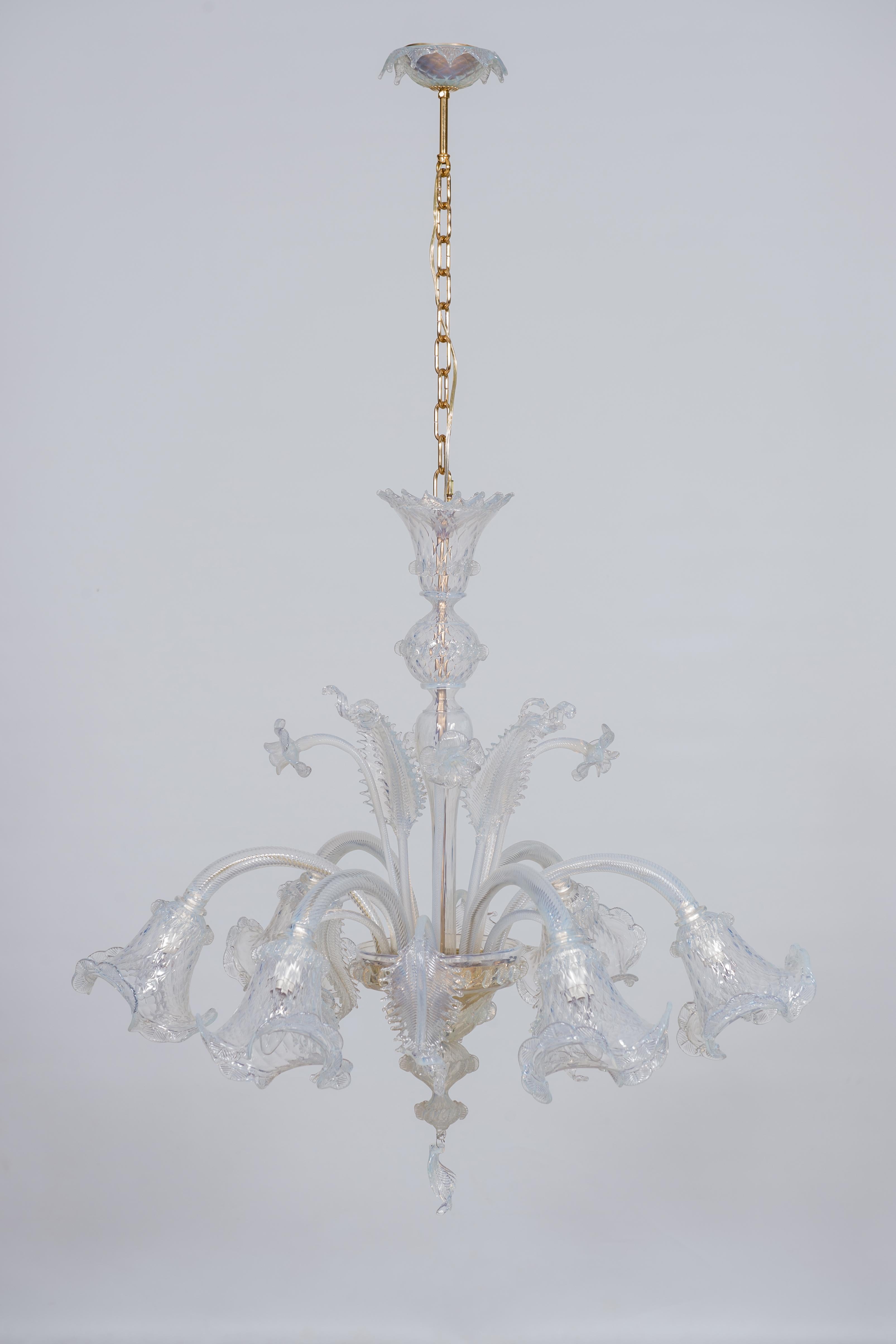 Cet exquis lustre en opaline, fabriqué à la main sur l'île de Murano dans les années 1960 (région de Venise, Italie), se distingue par ses décorations florales colorées qui virent au bleu clair. Six bras opalins munis d'ampoules dépassent du lustre