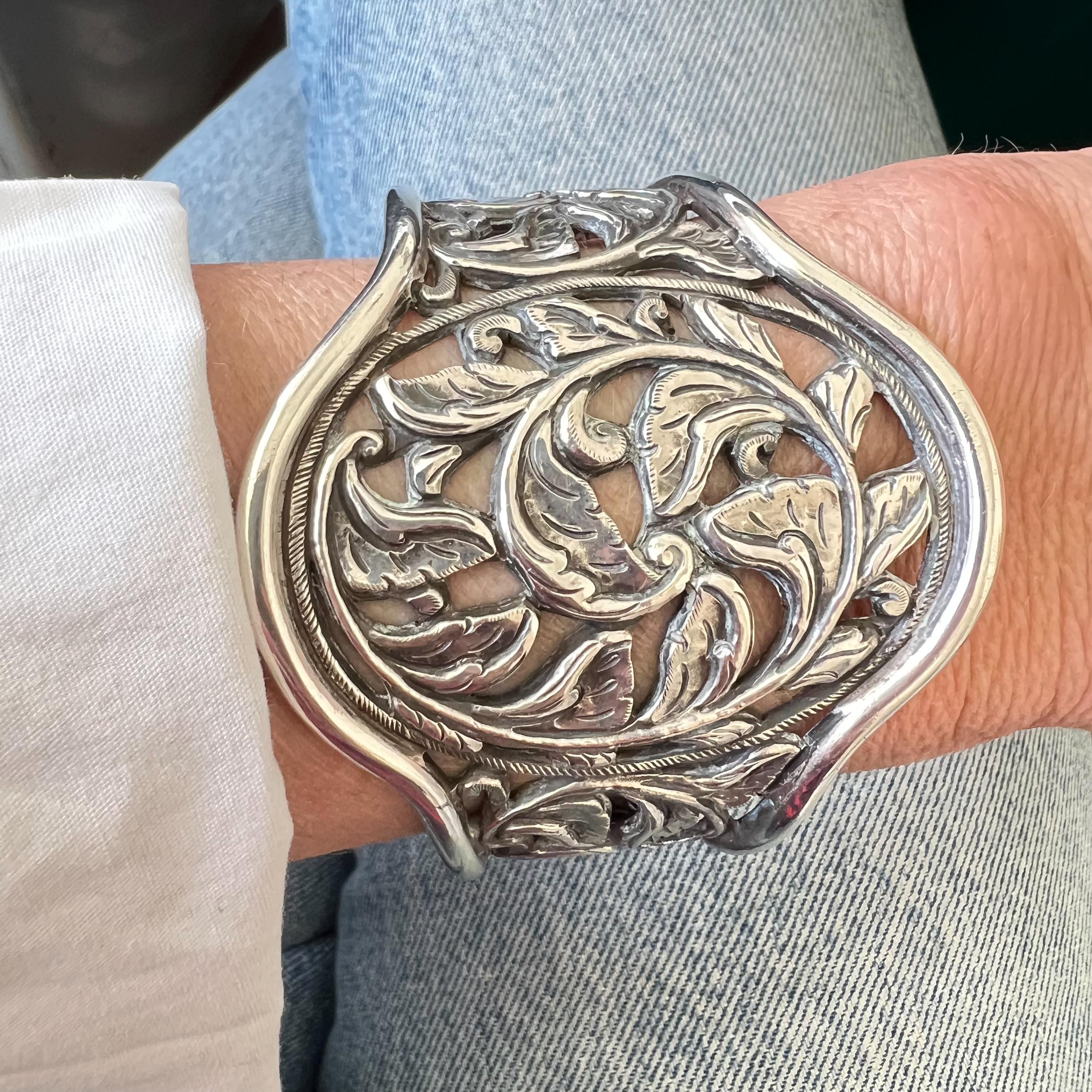 Esta impresionante pulsera brazalete vintage es una hermosa pieza de plata de alta calidad, con un intrincado calado floral que la convierte en un llamativo accesorio estético y funcional. La pulsera combina un delicado arte con una construcción