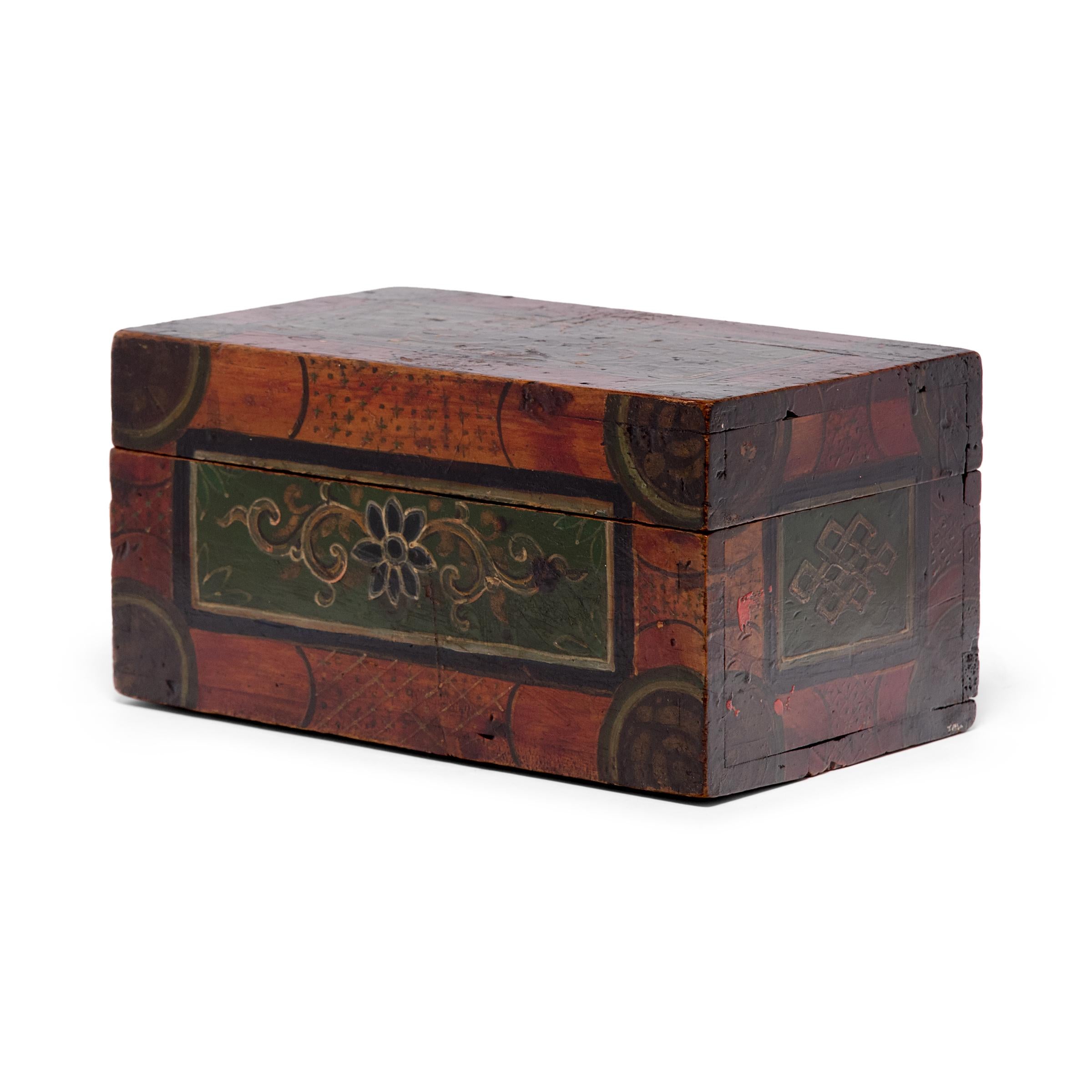 This vintage box dates to the early 20th century and is decorated in the style of Mongolian and Tibetan furniture. The exterior is painted with chrysanthemum blossoms and endless knots, Buddhist symbols of endless wisdom and compassion. Painted in a