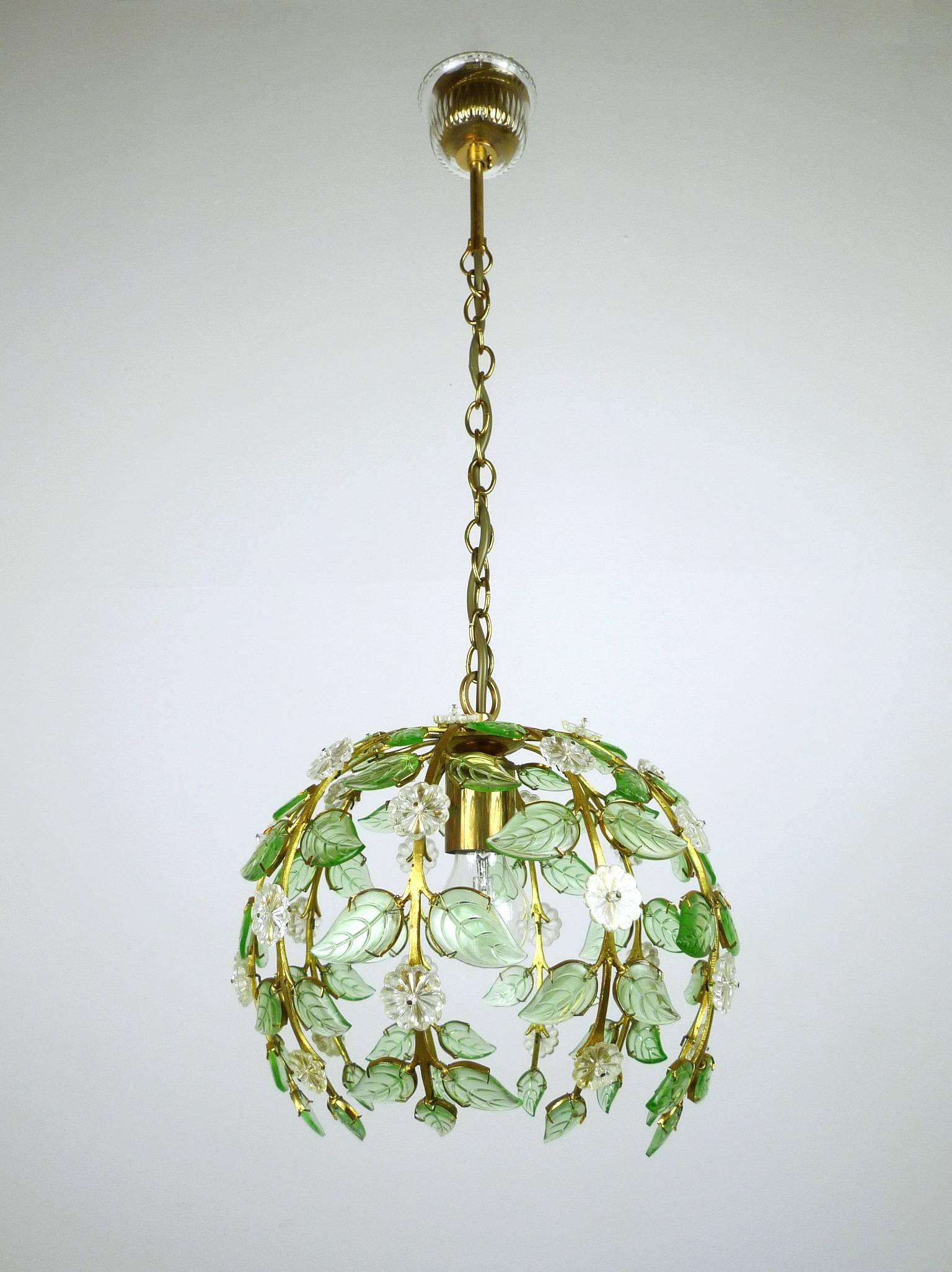 Translucent floral pendant lamp from the 1960s made by Palme & Walter KG in Germany.
Ten branch-shaped gilded metal arms hold alternating green plastic leaves and clear flowers. The body of the lamp has a brass chain suspension and closes to the