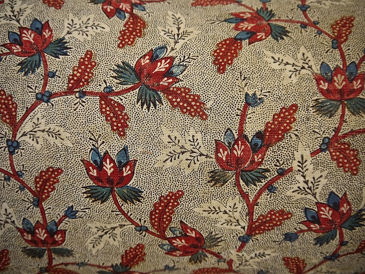 French 18th century block printed textile with a design of red stylized flowers and leaves on meandering branches with touches of blue on a picotage ground. Lightly quilted. Backed in a natural indigo dyed French 19th century linen. Slip-stitched