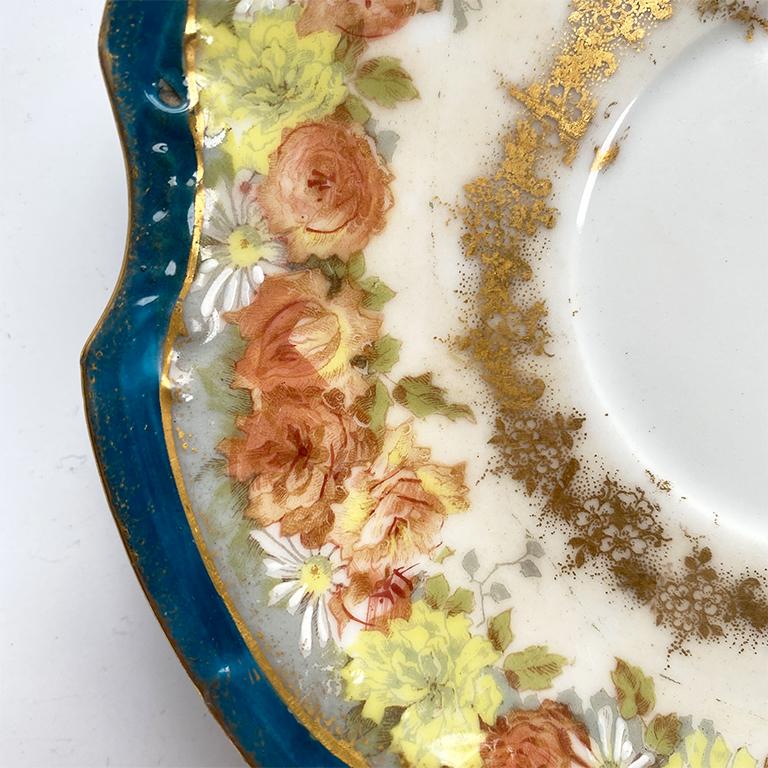 A beautiful Coiffe Limoges floral plate. Doesn't this pretty saucer remind you of Gucci? A rich blue decorates the scalloped edges at the outer rim, and hand-painted flower bouquets in orange and yellow are around the center. Gold accents are