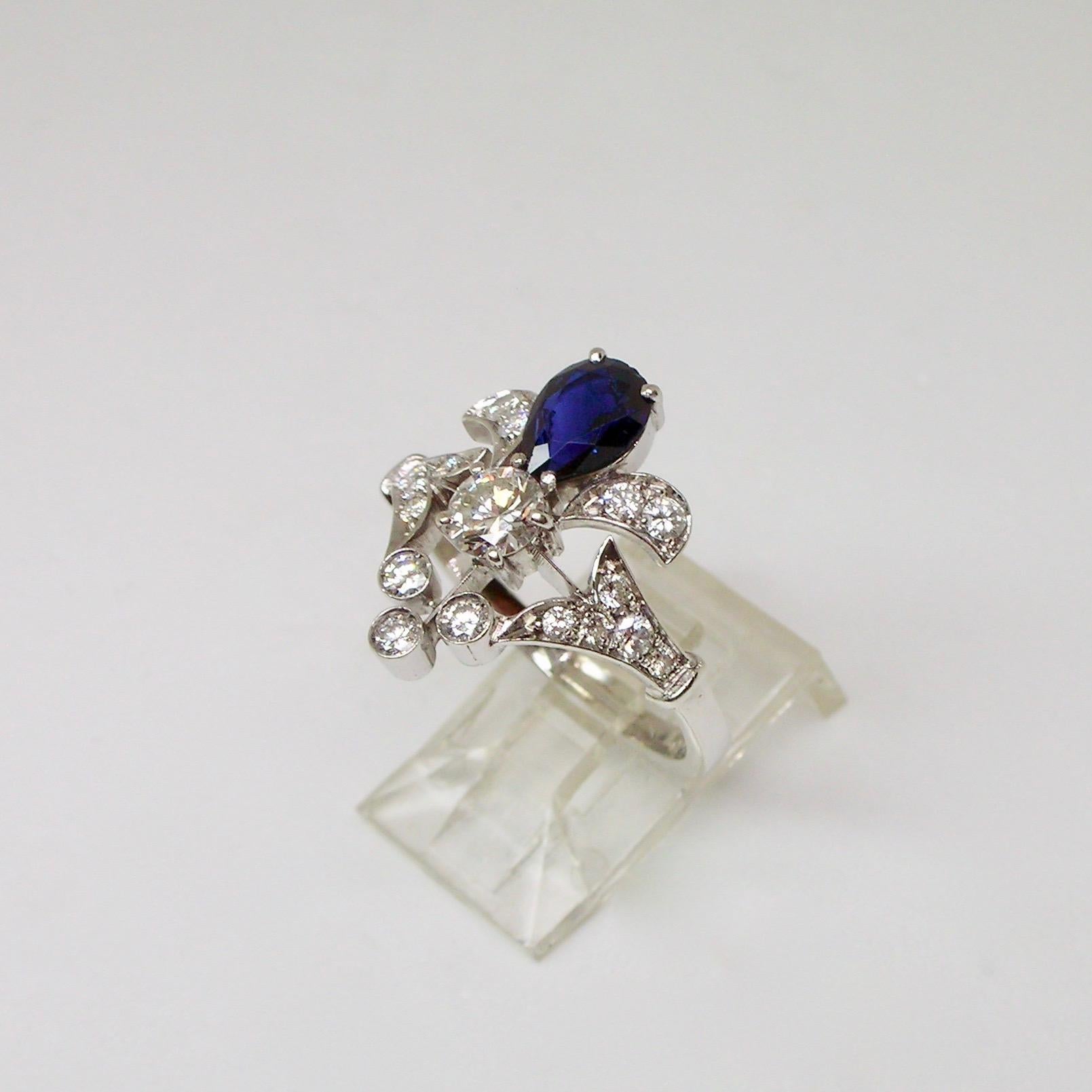 Floral design ring set in 18 carat white gold with round cut diamonds for approximately 1 carat total weight and a drop cut natural sapphire of good intense blue. 
Ring from the 1960s period circa.

Italian ring size: 16.5

