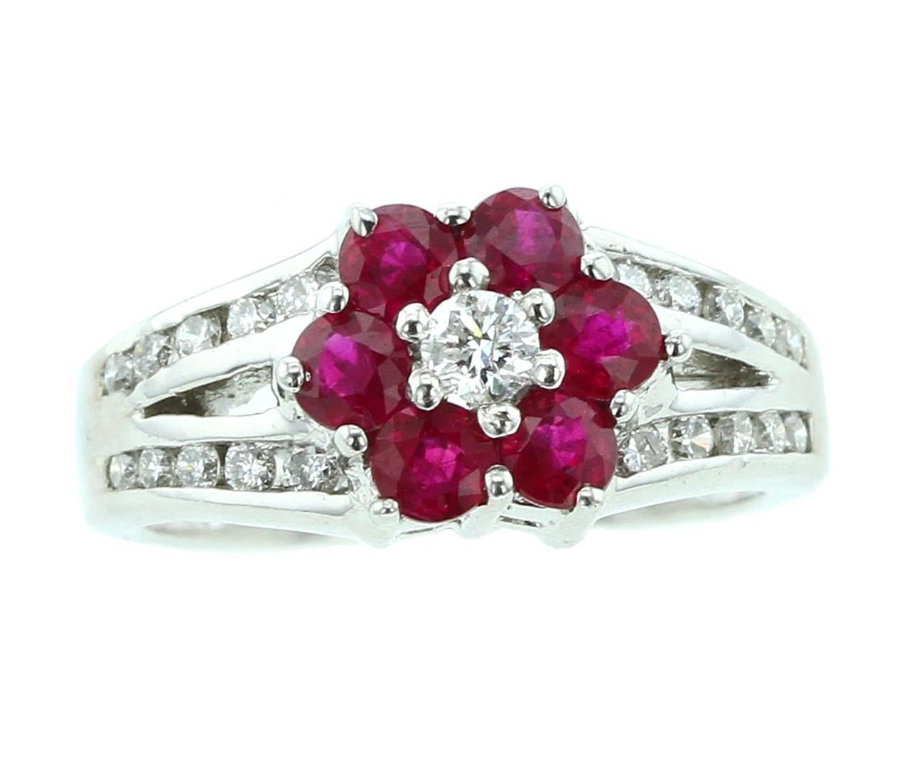 A floral ring comprising of six round red rubies with a center diamond, accented with twenty diamonds on the mounting, 14K White Gold. 
