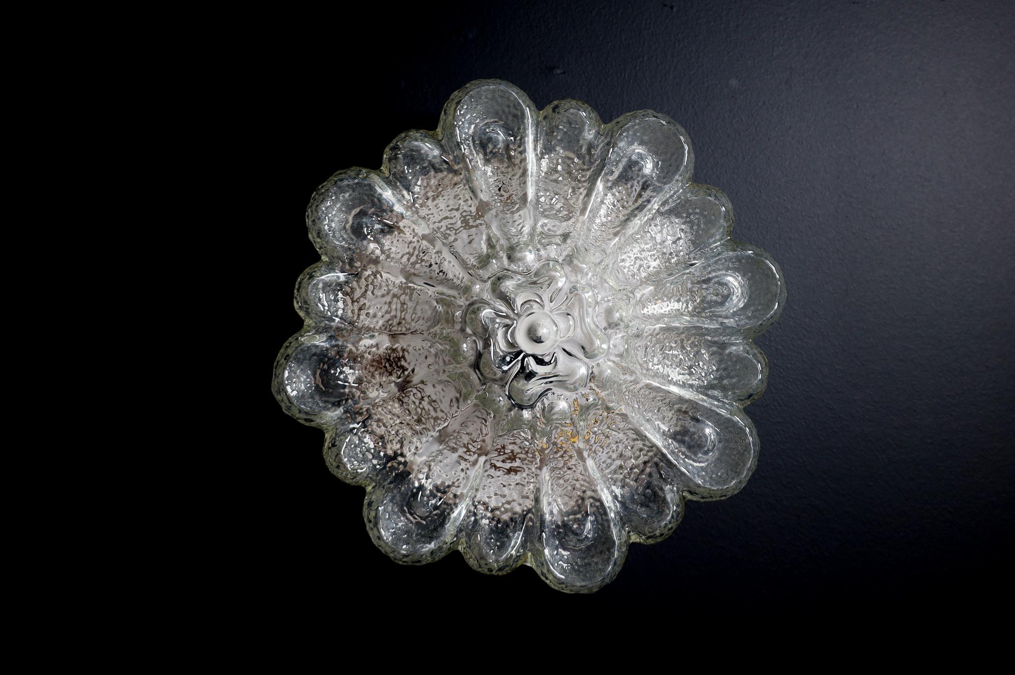 Floral shape flush mount or wall light Germany 1960s.

Floral shape flush mount ceiling light or wall light made of heavy textured clear iced glass made in Germany, 1960s. This midcentury vintage lamp illuminates beautifully, casting a warm glow