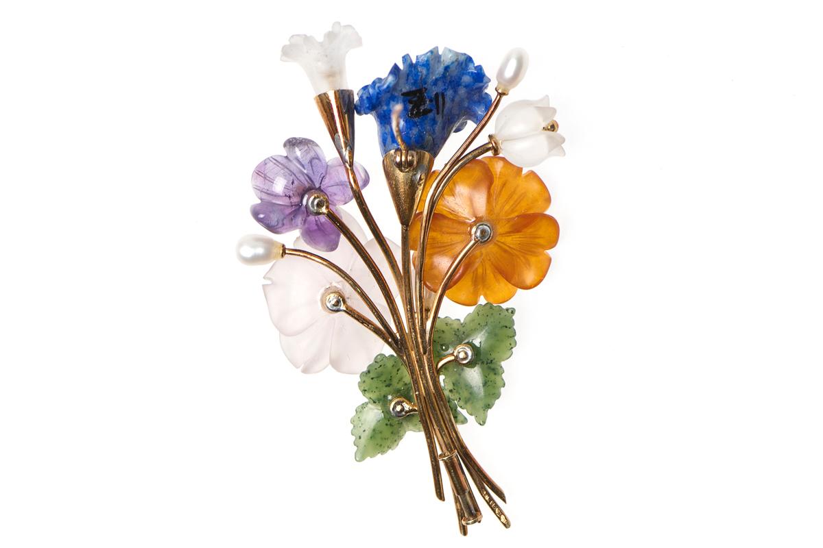 A floral brooch in the form of a spray set with carved stones in 14 karat gold. Beautifully crafted into a posy of flowers using nephrite, cornelian, lapis lazuli, amethyst, crystal and freshwater pearl with central collets of facetted peridot and