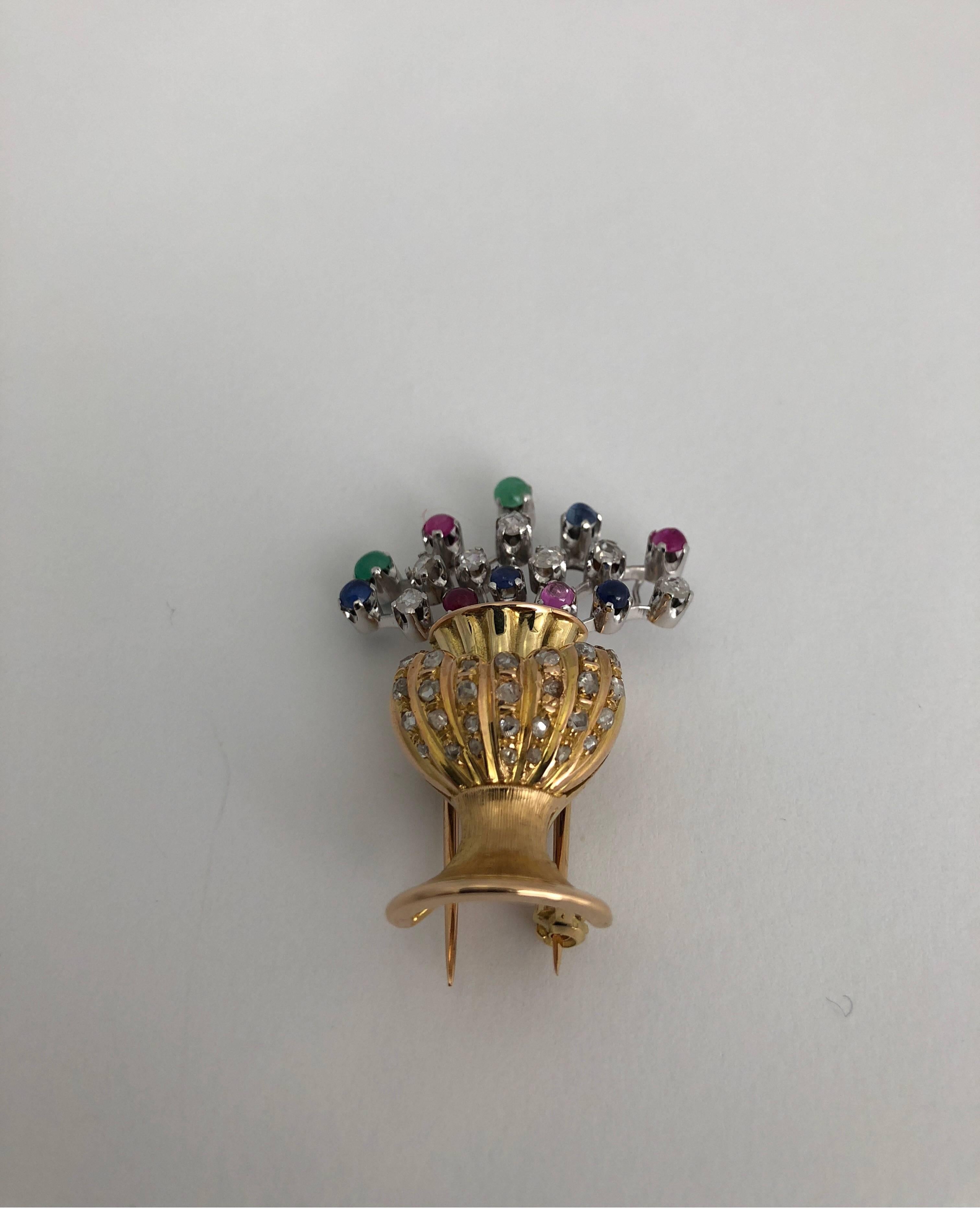 Floral vase brooch in yellow gold and and gemstones
total weight of gold 18 kt gold gr 14.80
total wieght of white diamonds ct 0.77 OLD CUT
total weight of  2 emeralds ct 0.18
total weight of 4 blue saphire ct 0.42
total weight of 4 ruby ct