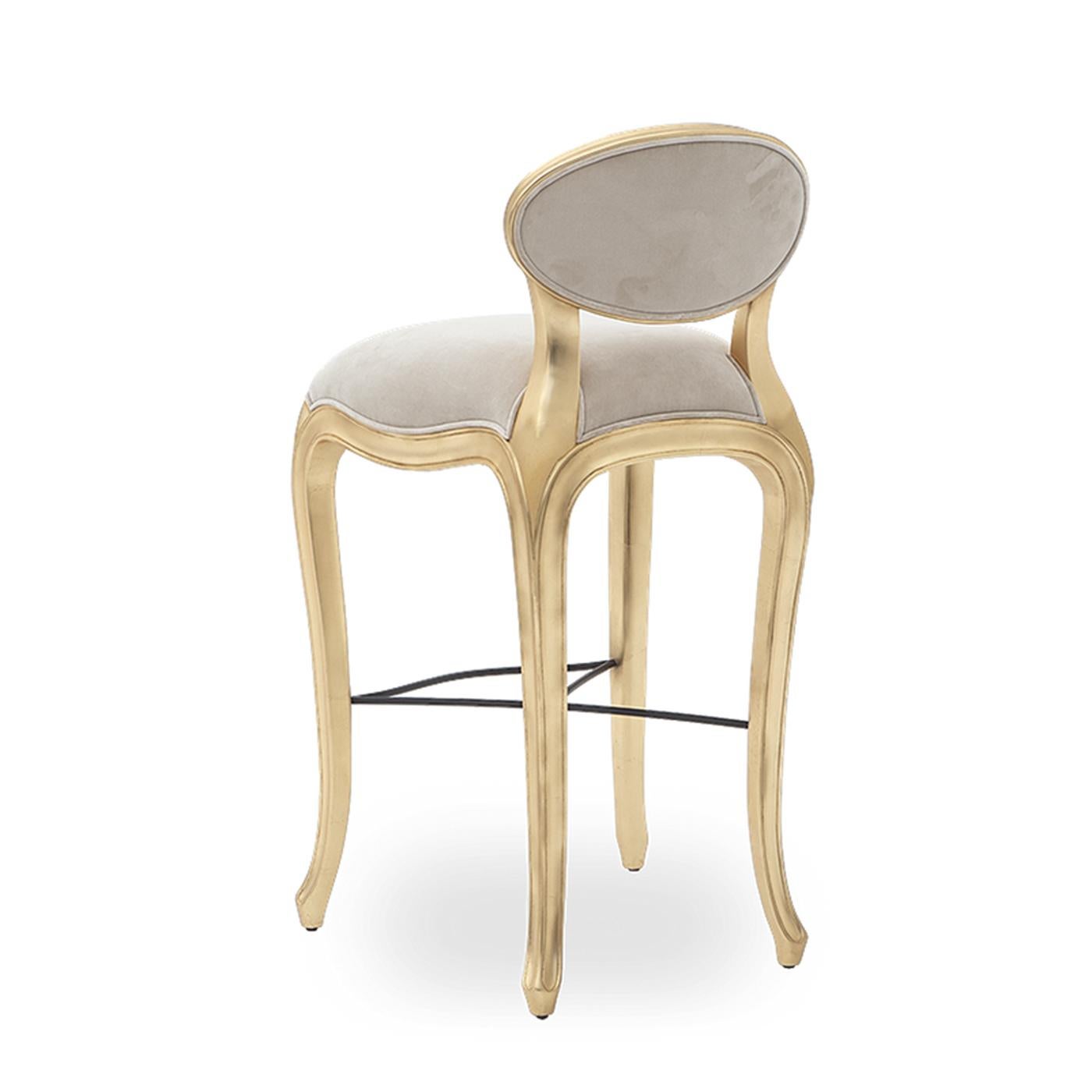 Barstool Flore with structure in handcrafted solid
mahogany wood in gold leaf finish, with cabriole
feet, with footrest. Upholstered seat and back
covered with high quality fabric Alcantara soft grey.
Seat dimensions: L 51 x D 44, seat height 80