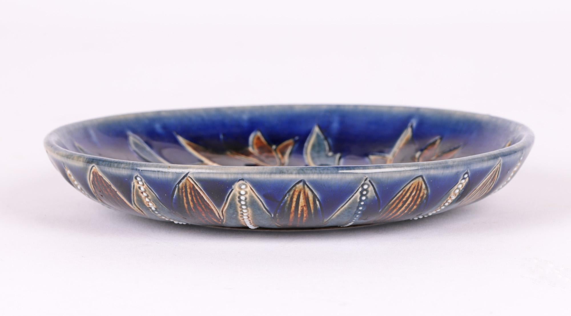 A scarce and finely made Doulton Lambeth art pottery pin dish decorated with trailing floral designs by renowned artist Florence E Barlow and dated 1879. The small round stoneware dish stands on a narrow round unglazed foot with slightly recessed