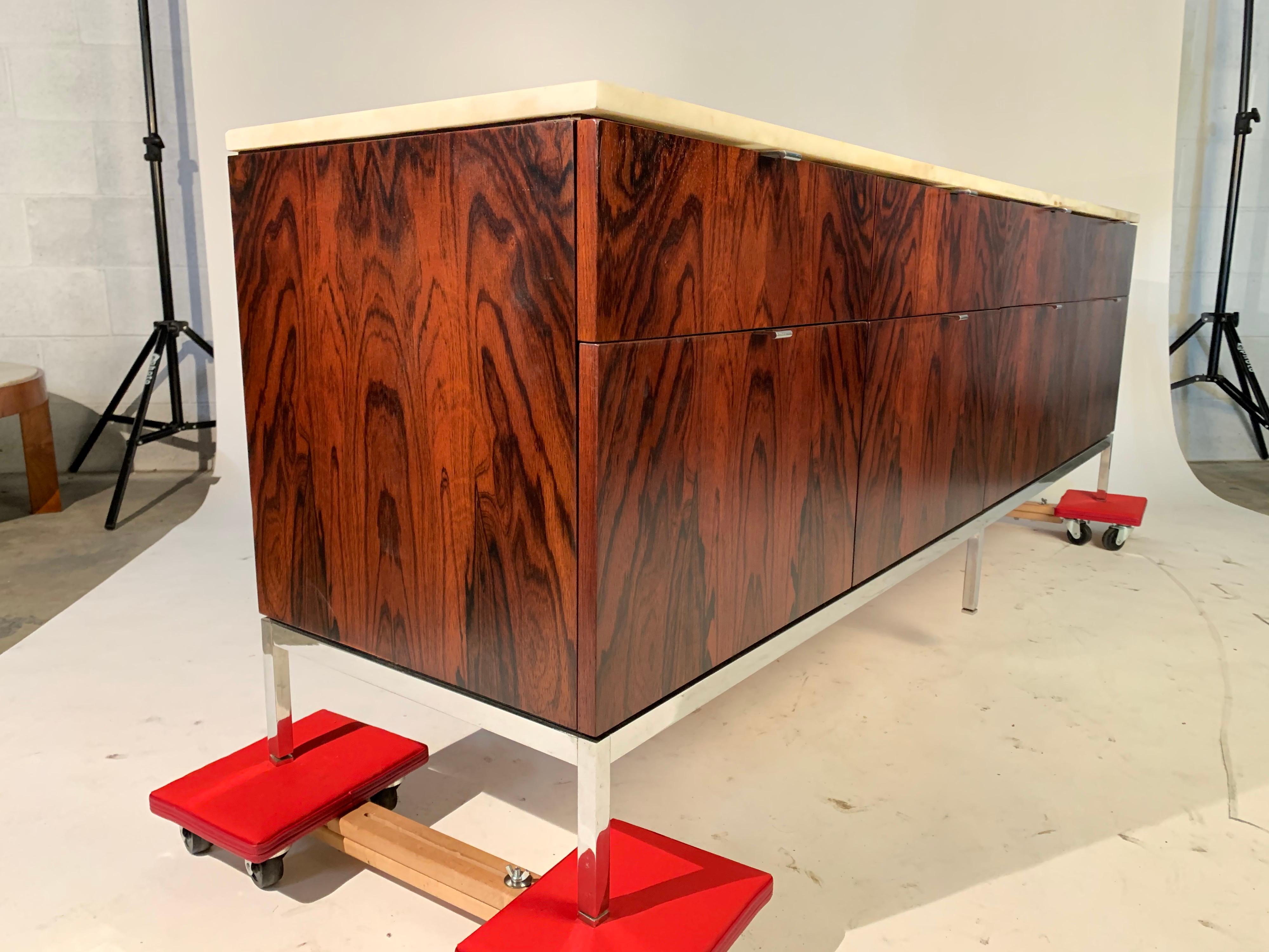 Florence Knoll for Knoll International rosewood and marble top 8-drawer credenza having chromed steel base. Features 2 file drawers and ample case storage. 
This example has outstanding grain that is rarely seen on these cabinets. It’s is truly