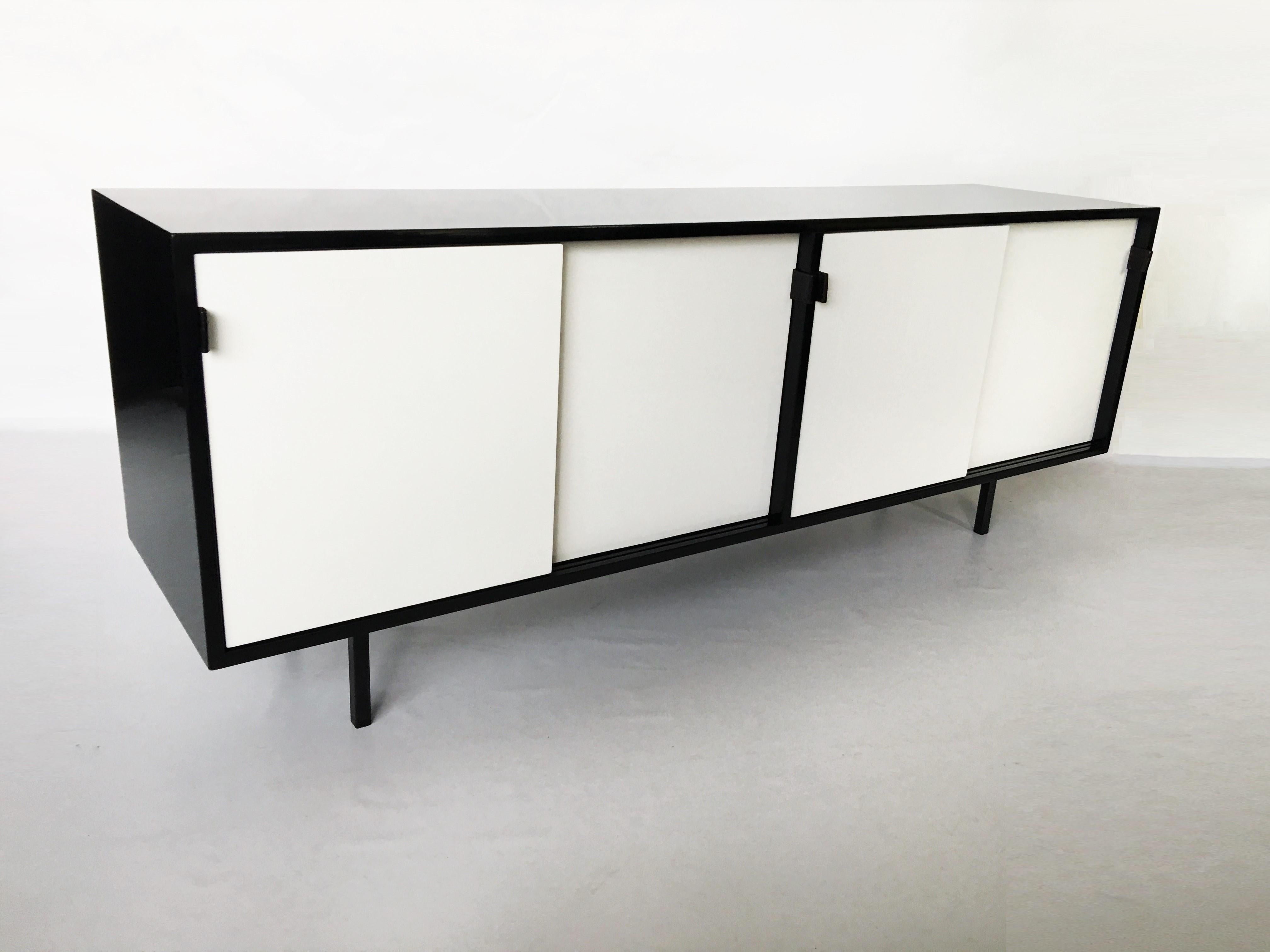 A modern take on the Classic, presented is an eye catching black and white lacquered sideboard/credenza designed by architect and designer Florence Knoll and manufactured by Knoll Associates Inc, circa 1950s. The cabinet features four sliding doors