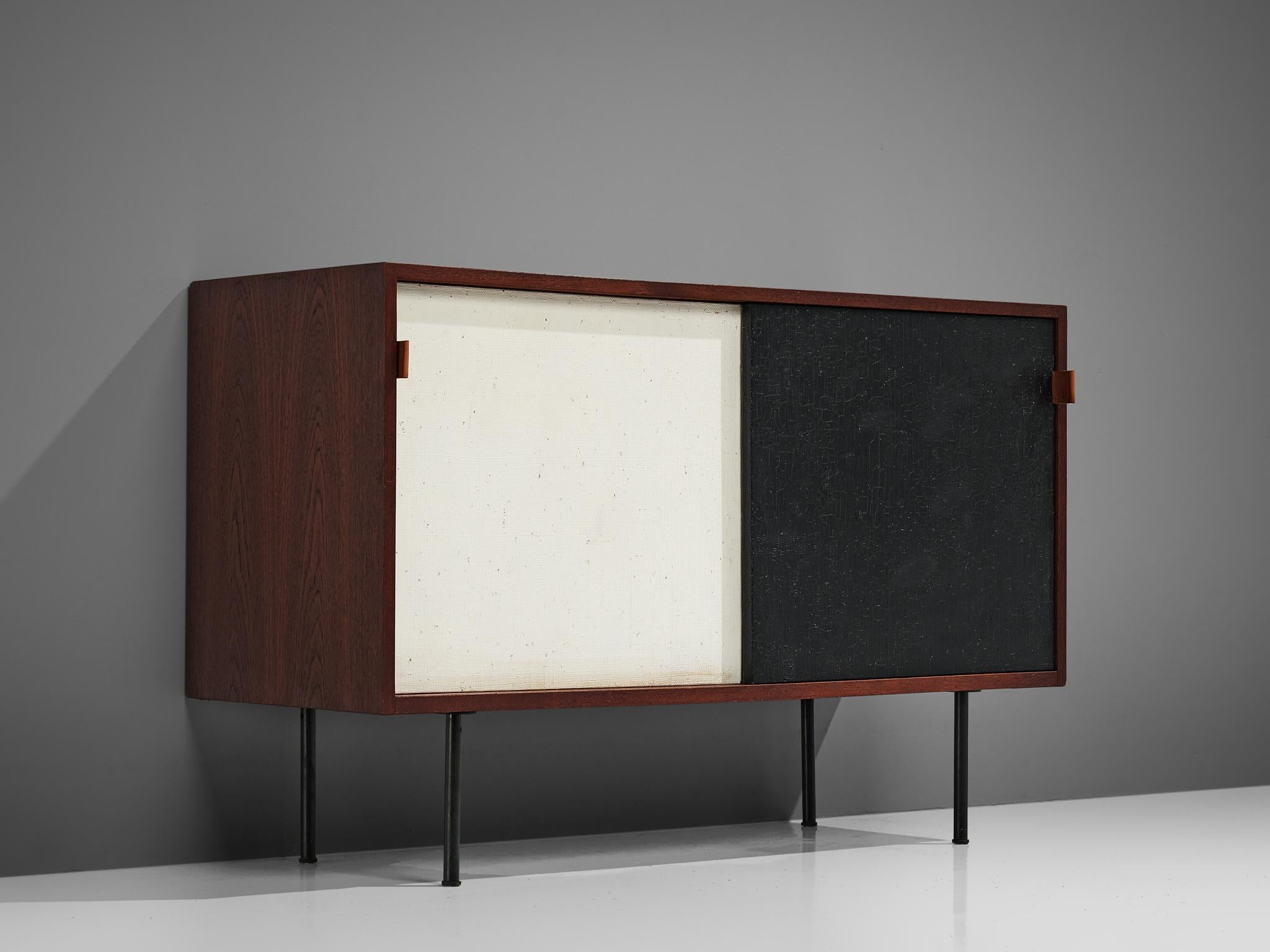 Florence Knoll for Knoll International, sideboard, teak, metal feet, leather straps, Germany, produced 1986, designed 1960s

Sideboard in teak with two sliding doors in black and white. The credenza is equipped with two shelves on the right and