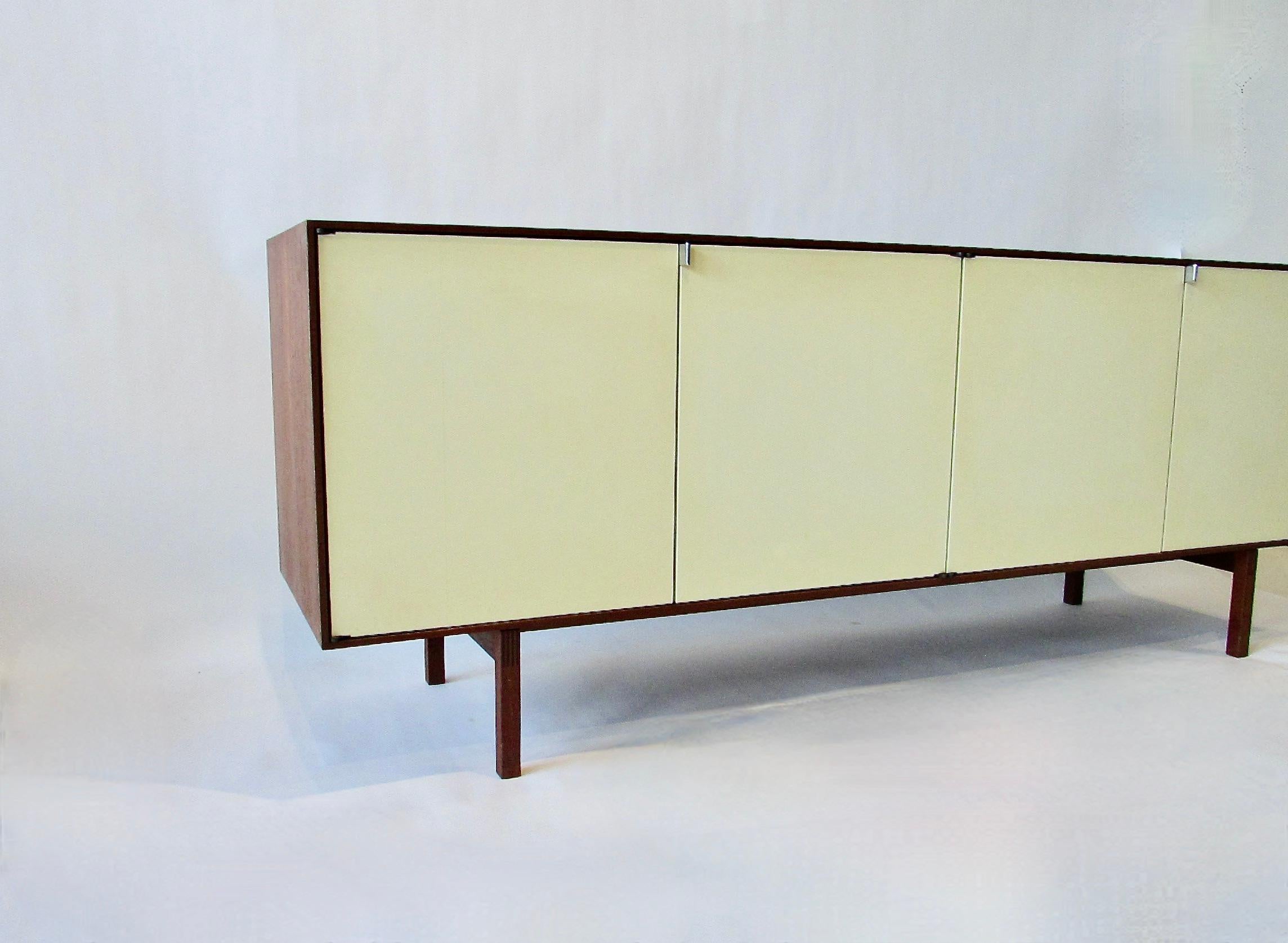 Very clean and original early Florence Knoll for Knoll Associates Credenza. Teak cabinet  with cream doors and maple veneer interior .  Left side of cabinet holds two drawers  and two adjustable shelves . Right side is fitted with two wider shelves