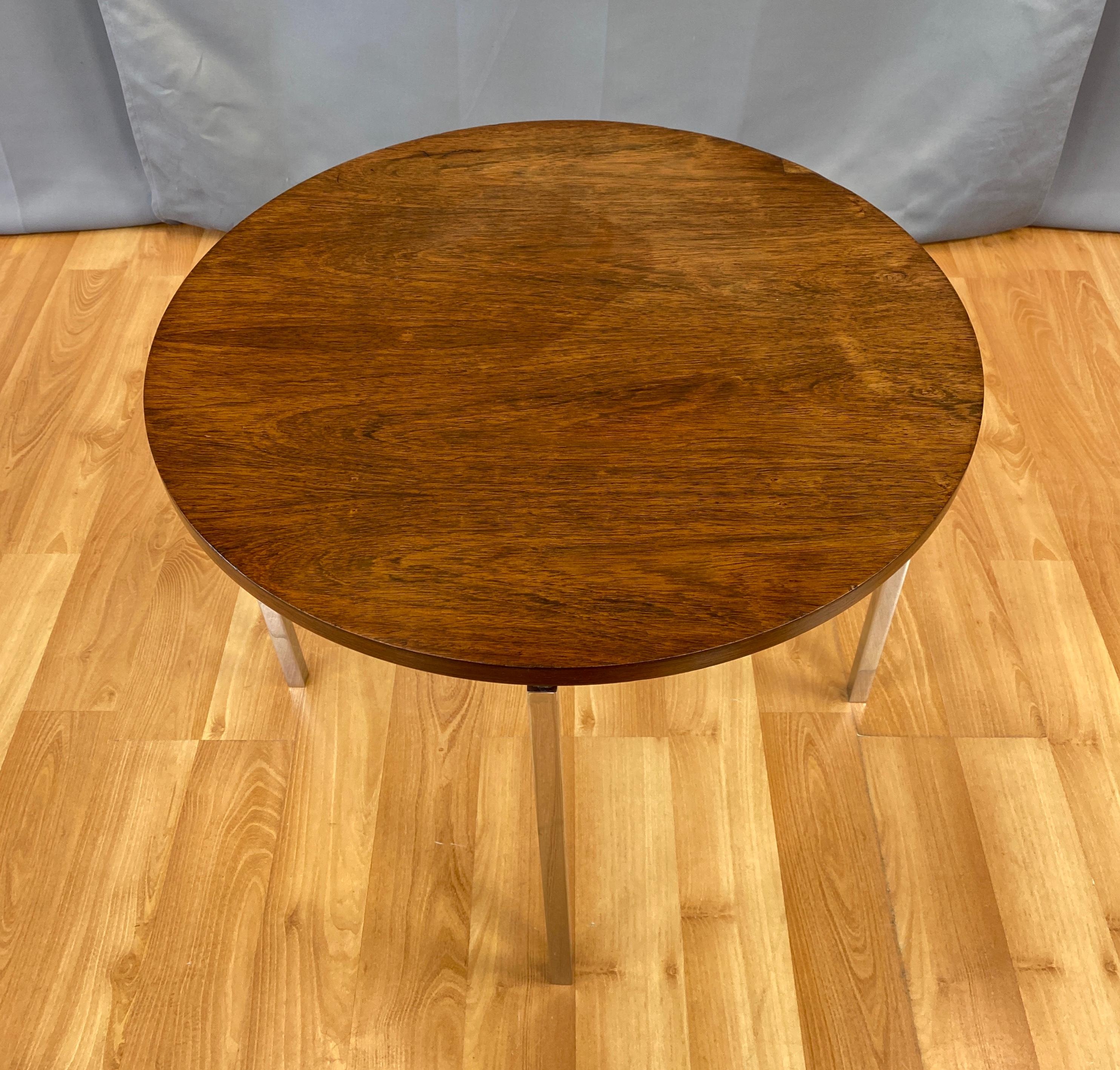 A 1960s round side table in rosewood with polished nickel base by Florence Knoll for Knoll Associates.

One of Knoll’s less commonly found designs, made even more rare by a striking Brazilian rosewood bookmatched veneer finish. Round top floats on a