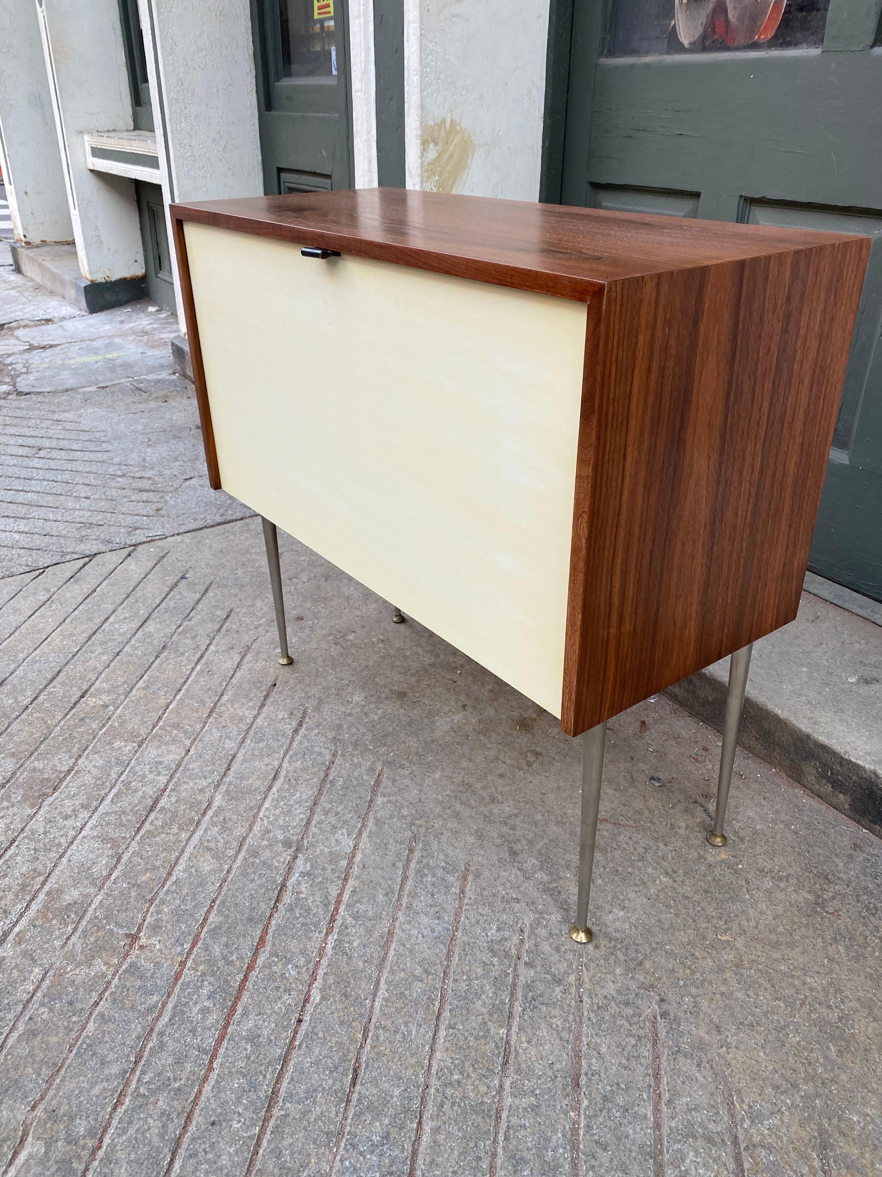 Florence Knoll for Knoll Hanging or standing Cabinet.  Always meant to hang from the wall, last used as a bar.  Added feet for ease of placement.  Walnut outer cabinet, and cream colored door that folds down.  Adjustable shelf and open area on right