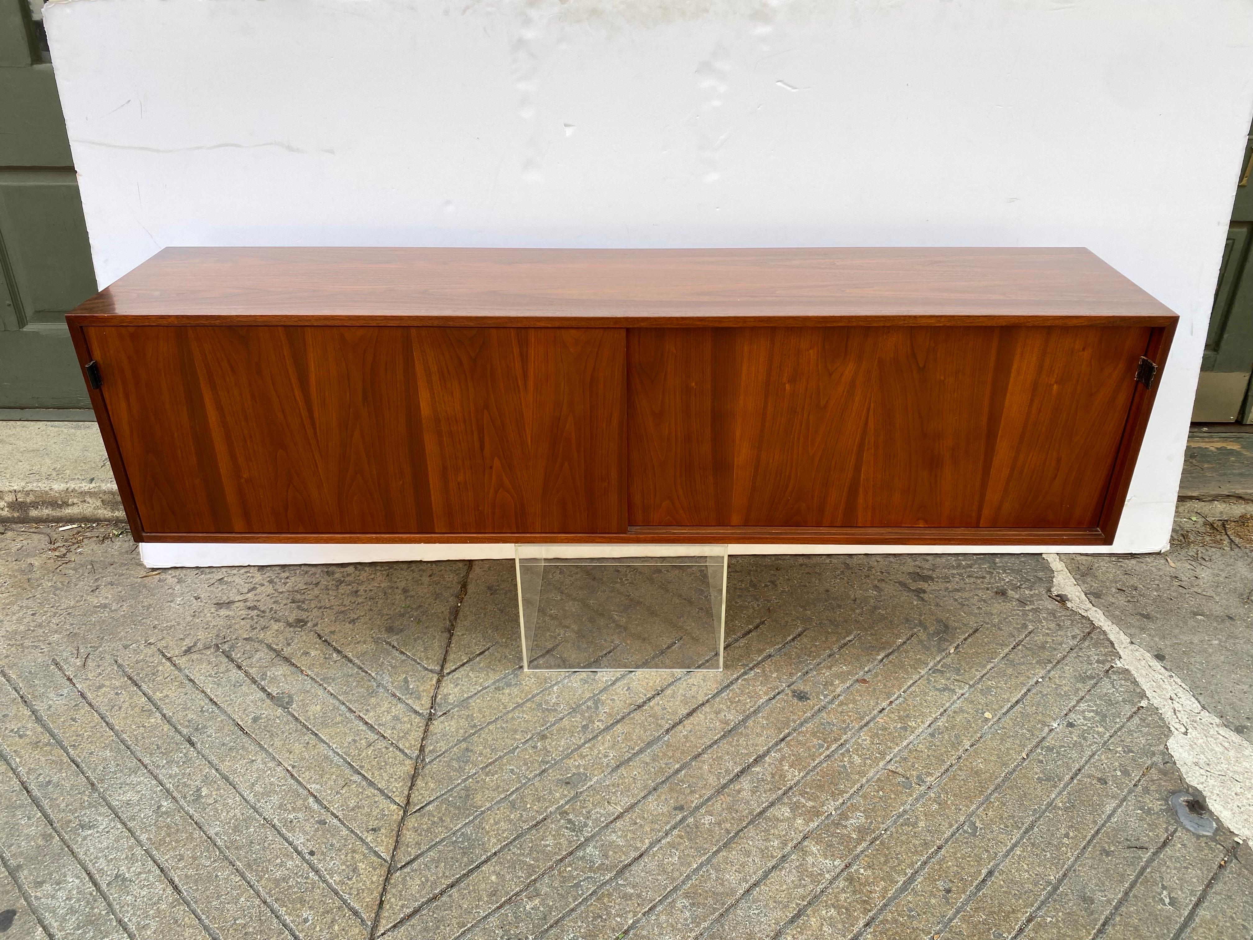 Florence Knoll for Knoll walnut hanging credenza/ cabinet. two doors slide open to reveal shelves and open storage. Iconic Knoll Design, extremely useful and good looking. Original leather pulls in nice shape. Top has been refinished, original paint