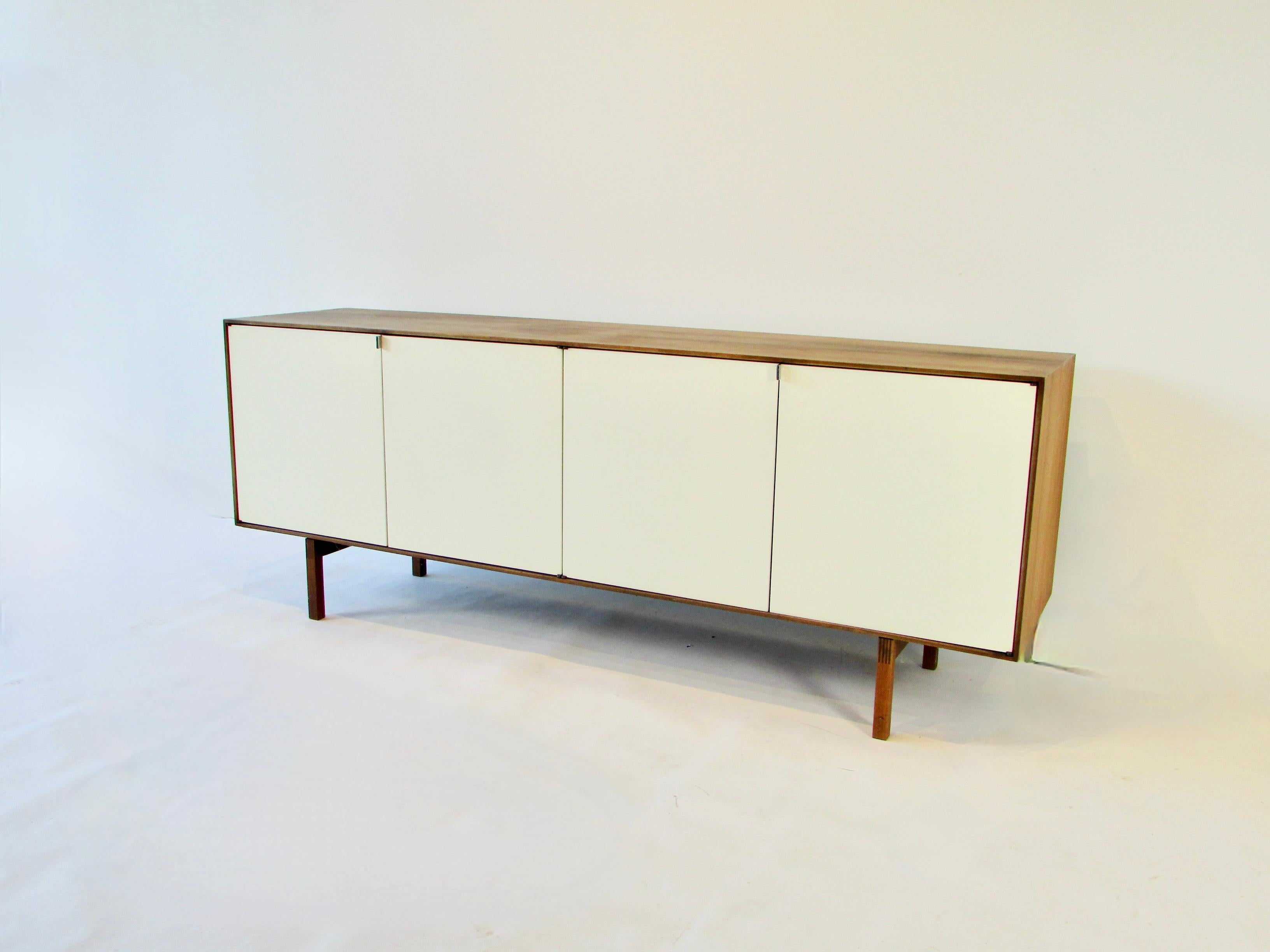 Florence Knoll design for Knoll. Walnut cabinet with four across lacquered doors on square dove tailed legs. Fitted interior of blonde maple includes four adjustable shelves and two drawers. Retains label on underside.
