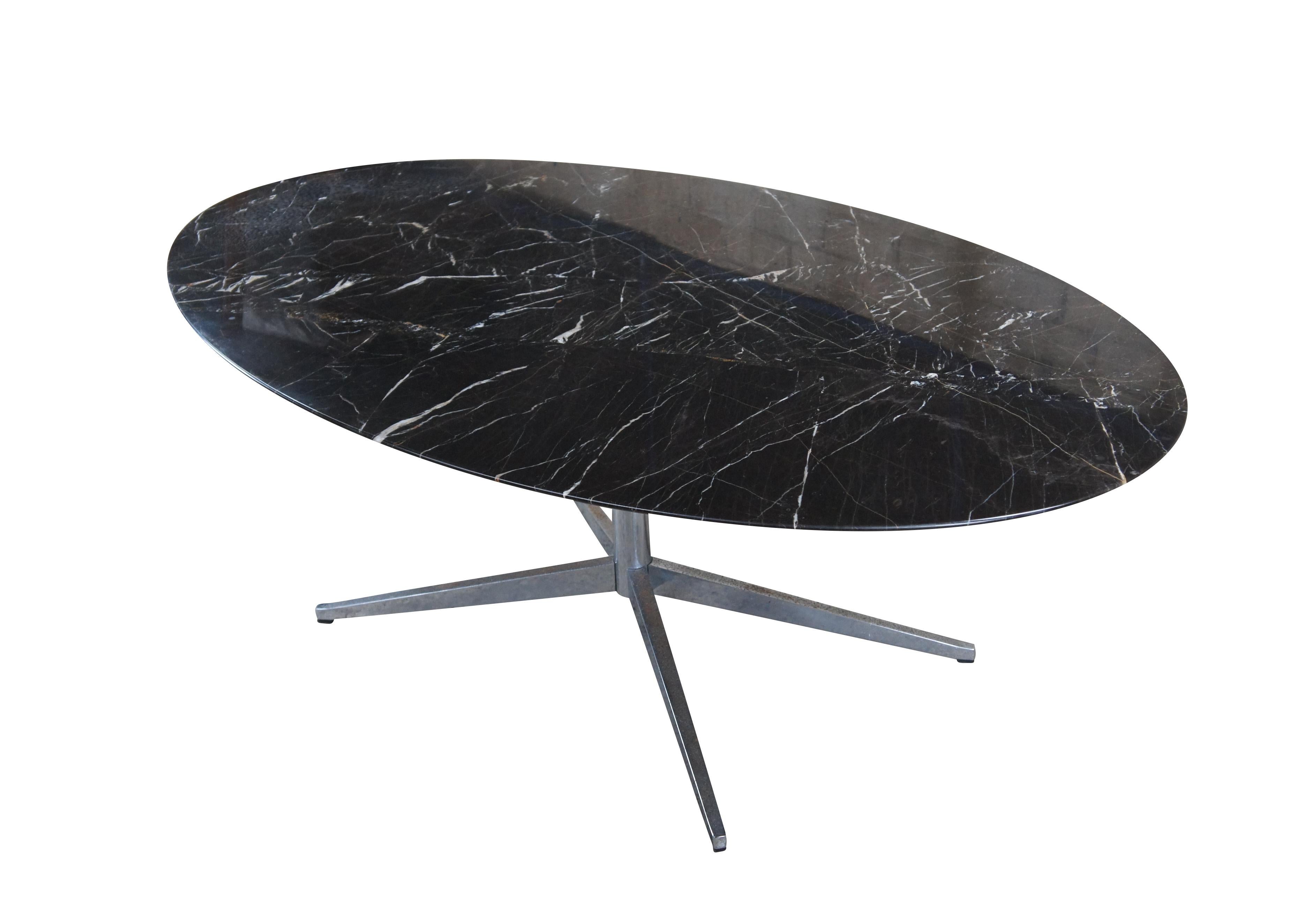 Une table de salle à manger / de conférence ou un bureau emblématique de Florence Knoll. Ce meuble présente un magnifique plateau ovale en marbre Marquina sur une base tripode en acier chromé, vers les années 1960.
