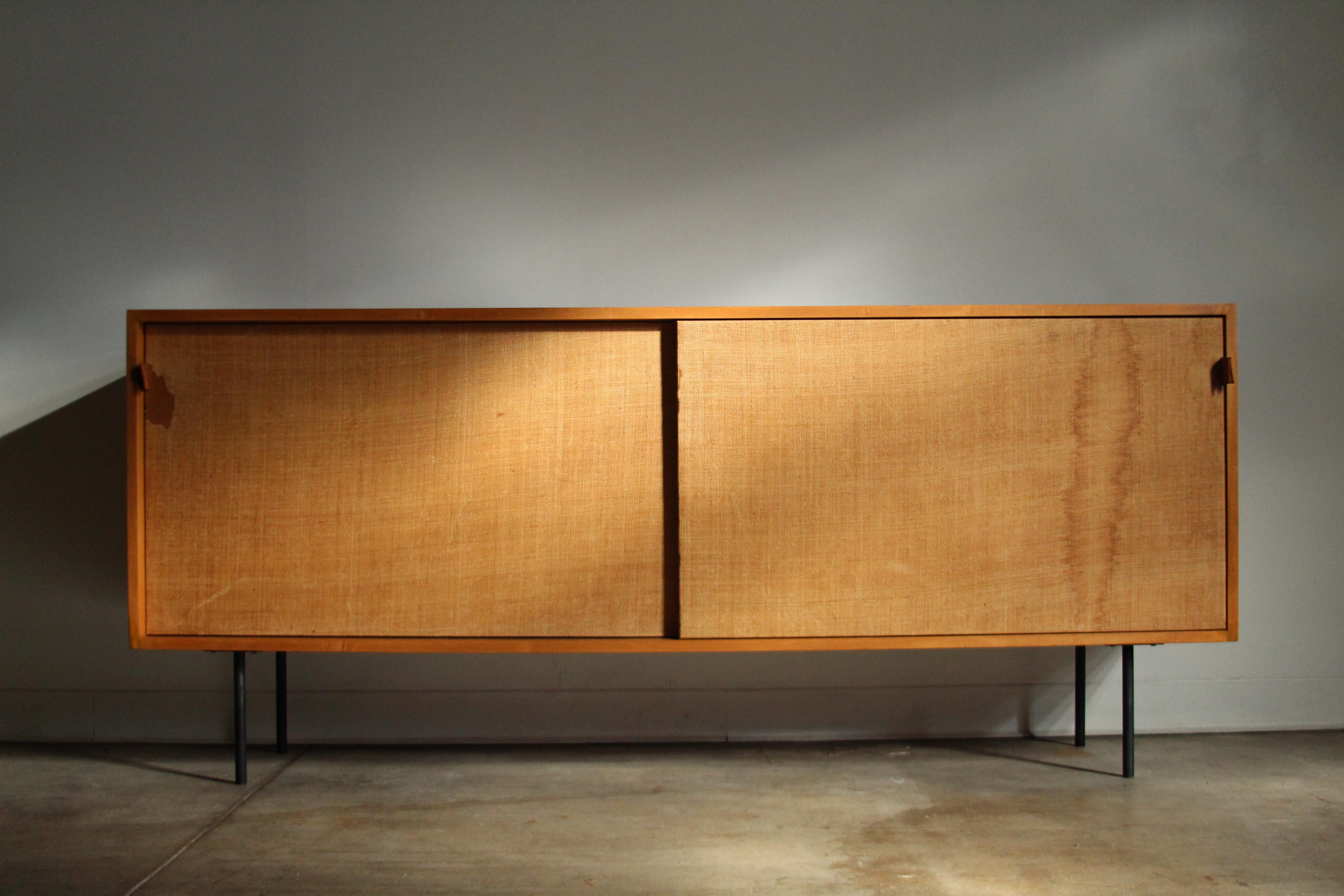 Ash, grasscloth and leather 'Model 116' cabinet designed by Florence Knoll in 1948 for Knoll Associates. The credenza features a pair of sliding doors with original grasscloth fronts and stunning, hand stitched saddle leather handles, opening to a