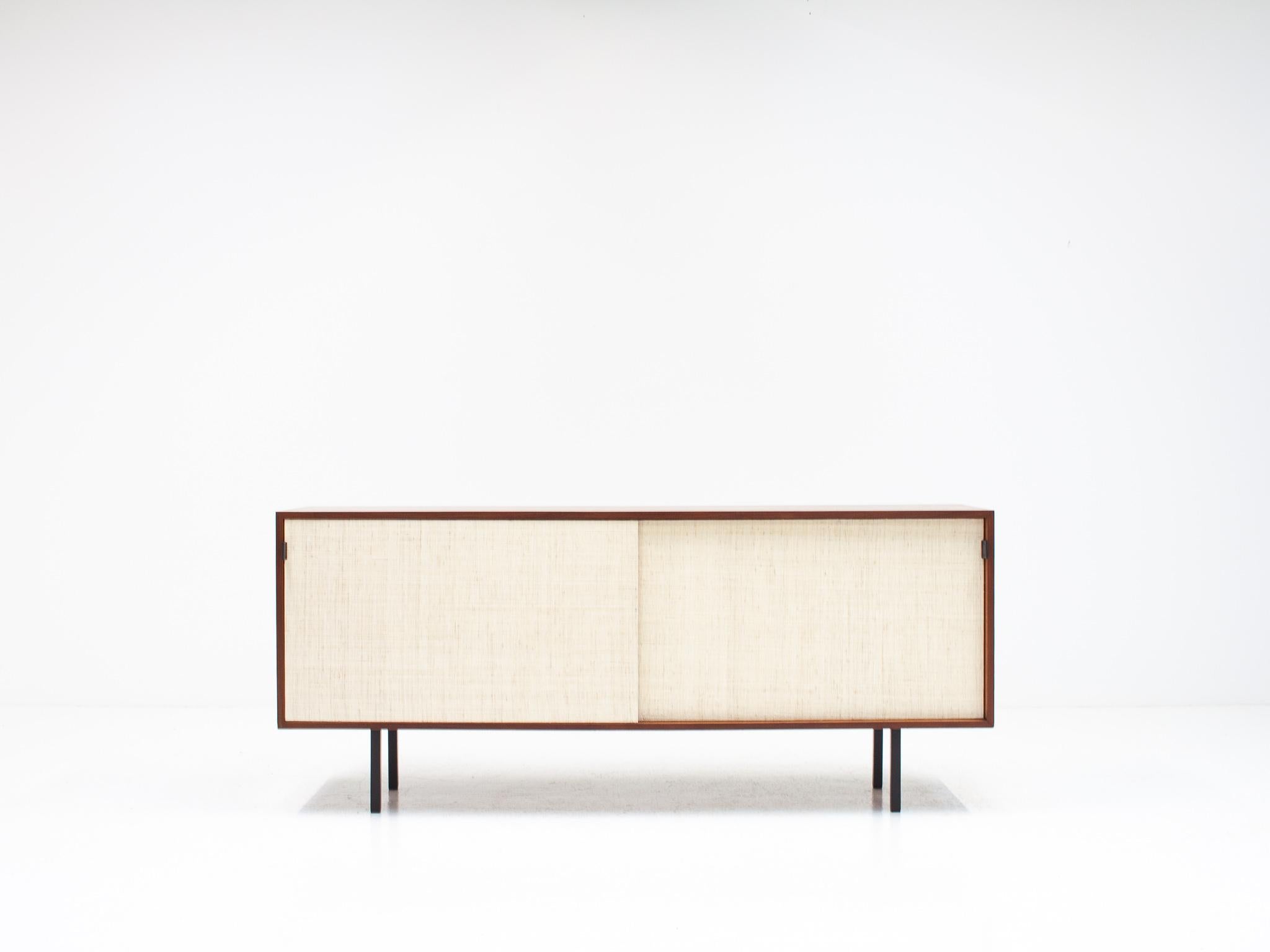 A rare 1950s Model 116 sideboard in teak with raffia fronted sliding doors and black leather pulls by Florence Knoll for Knoll International. Originally bought from Heals of London and we sourced directly from the original owner.

Enclosed within