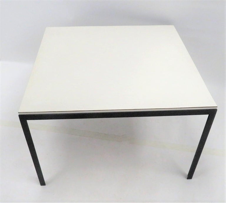 Designed by Florence Knoll and circa 1950, for Knoll Associates, a T-bar coffee or cocktail table in a white laminate top with black iron supports in the classic T-Bar form. 
Original condition with no restorations. No losses or