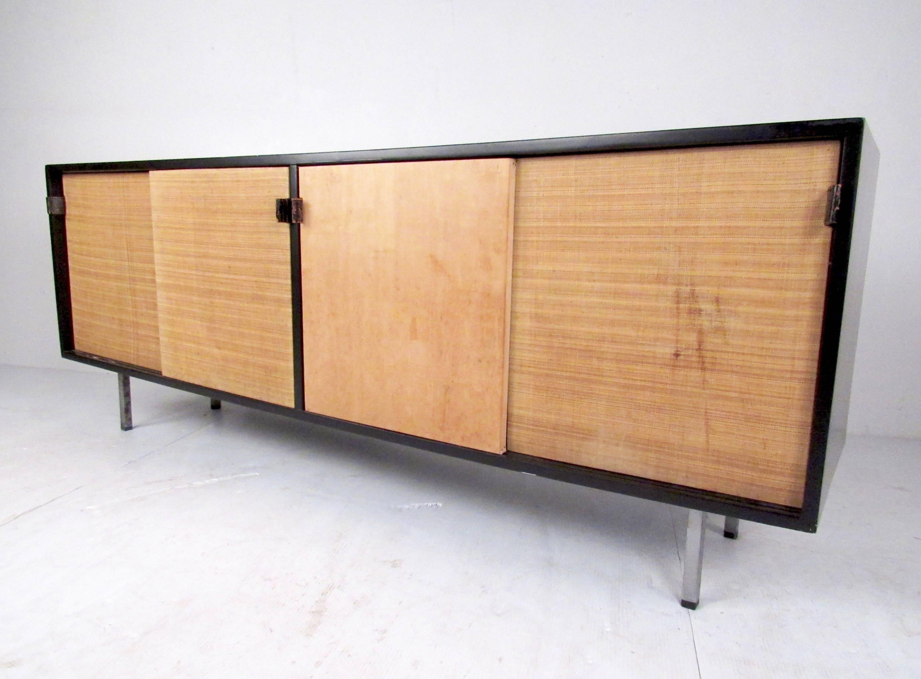 This stylish midcentury Florence Knoll credenza features cane front panels, leather door pulls, chrome legs, and quality Knoll construction. The lacquered finish contrasts wonderfully with the light colored cane doors while interior storage includes