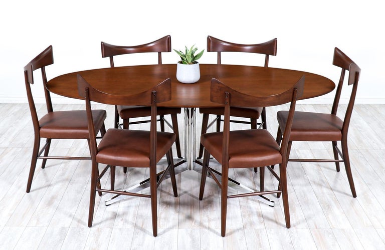 Versatile table designed by Florence Knoll for Knoll International in the United States circa 1960s. This iconic design features a solid oval walnut wood top that sits over a chromed metal post with four-star base perfectly proportioned to stand the