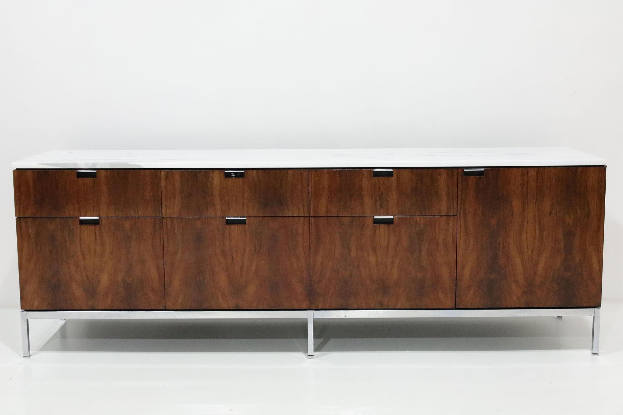 Florence Knoll's iconic sideboard/credenza in rosewood with marble top. The sideboard features 4 bays with internal shelving in one bay and file drawers and smaller drawers in three bays. Locking mechanism not available and keyhole covered to blend