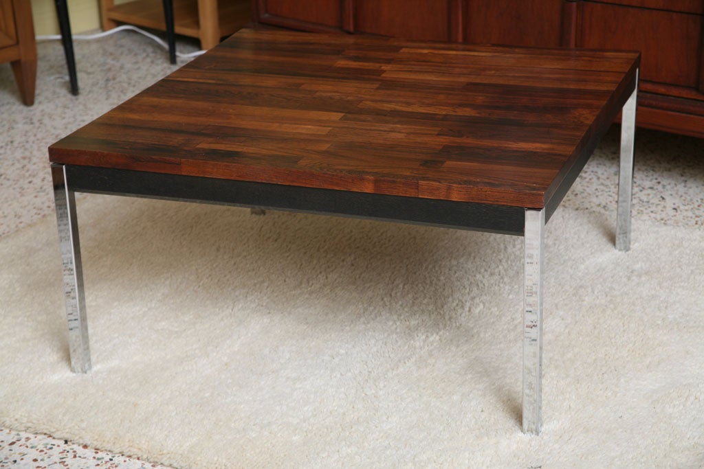 Beautiful and rich solid Brazilian rosewood in patchwork staved composition defines this modern table having an ebonized wood apron with a chamfered edge and supported by chromed steel squared tubular legs. Exceptional construction throughout, its