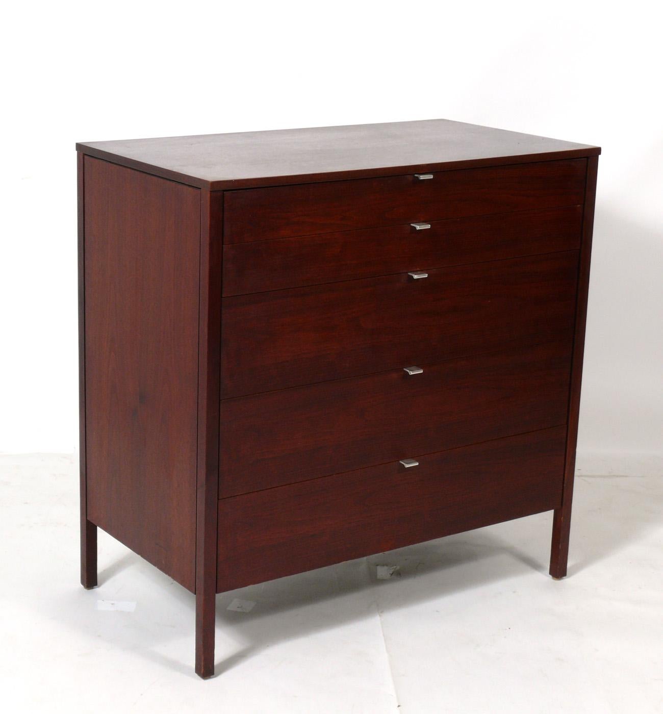 Clean lined mid century walnut tall chest, designed by Florence Knoll for Knoll, circa 1950s. It offers a voluminous amount of storage with five deep drawers.