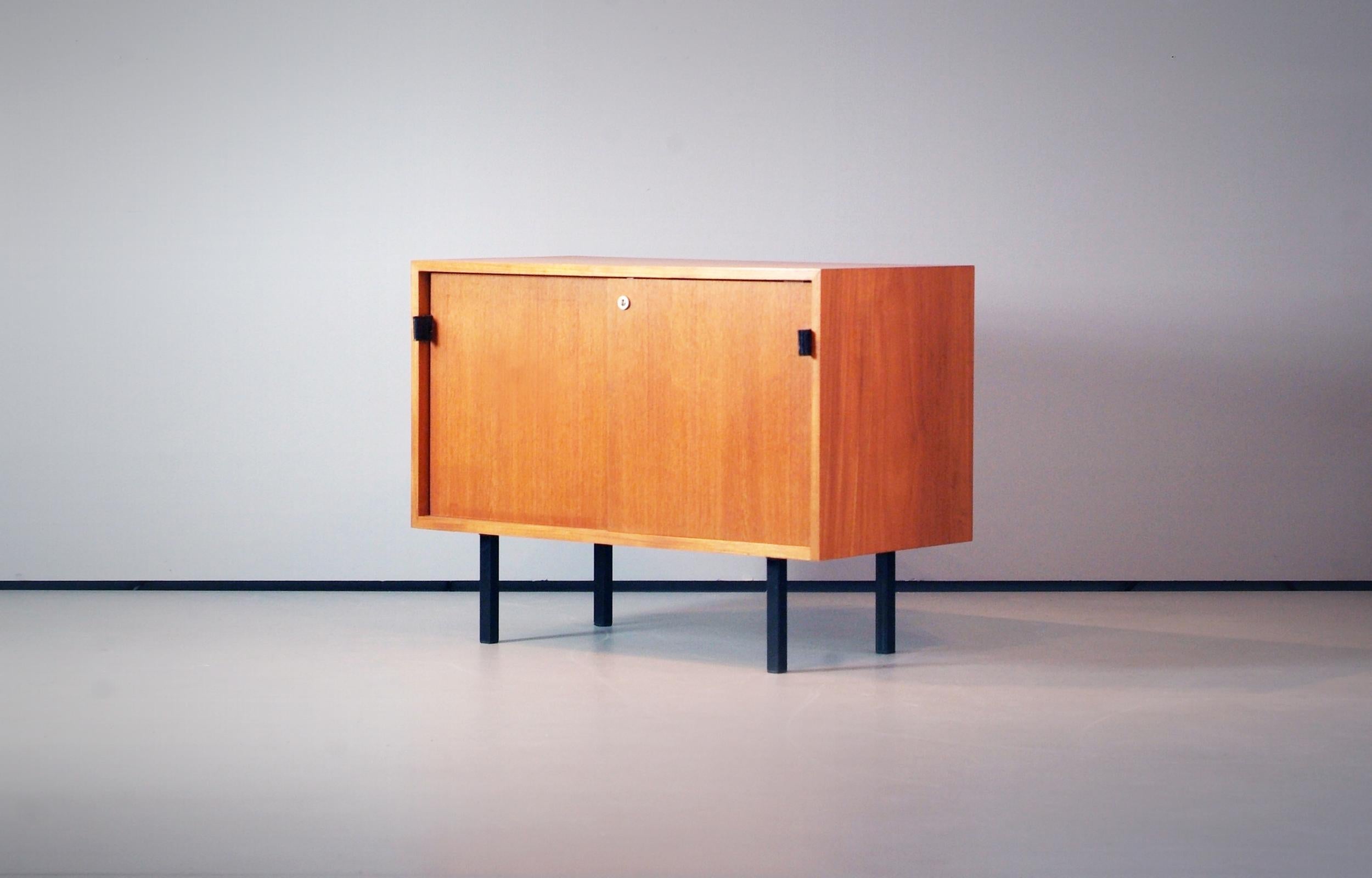 Beautiful small version of the legendary credenza / sideboard collection designed by Florence Knoll and made by Knoll International. Wonderful grained Teak, black leather handles and black metal feet. Signed with early 1960s sticker inside and with