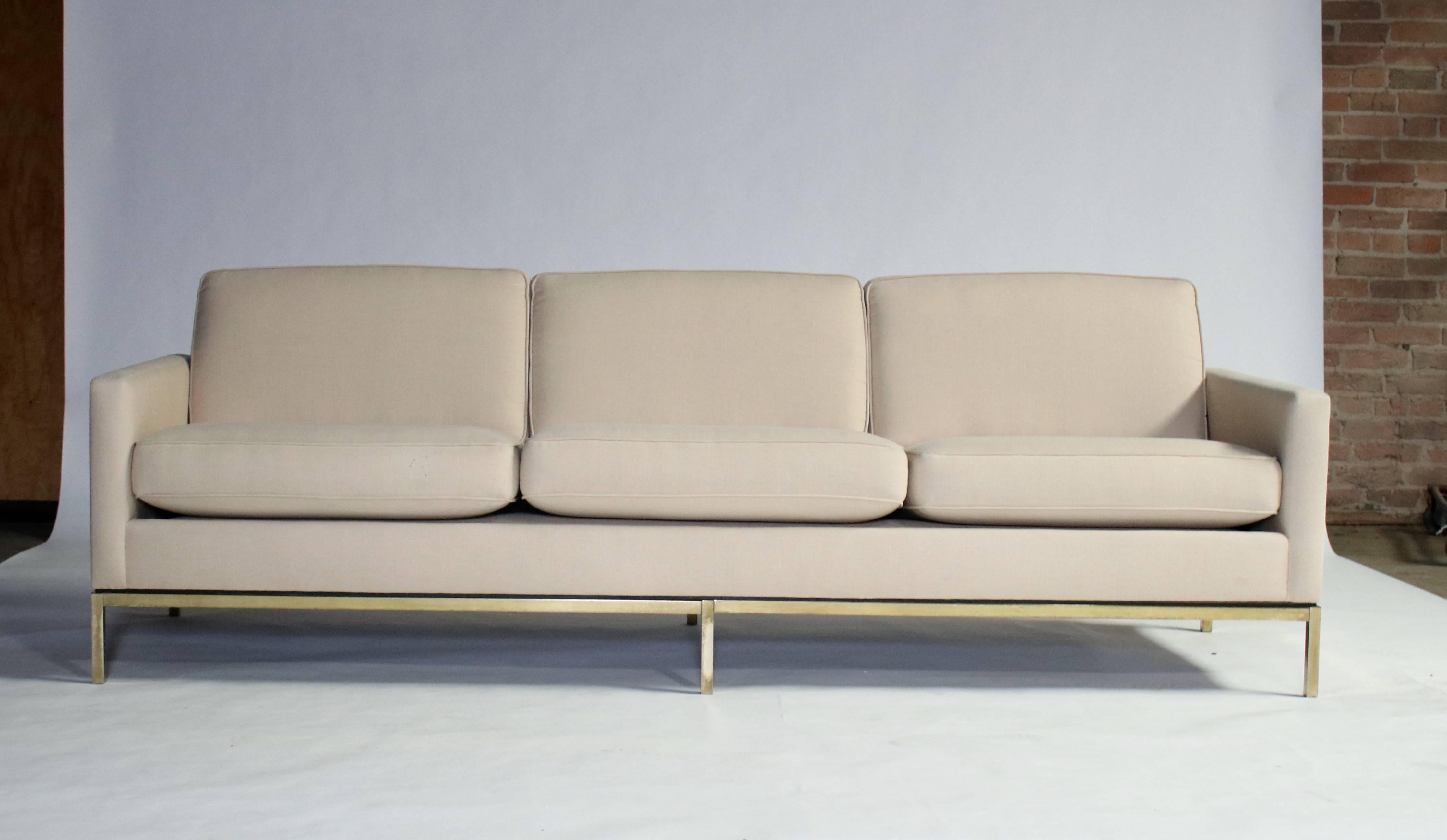 Three-seat sofa by Florence Knoll for Knoll Associates in cream color linen on a steel frame. Removable cushions. Gold tone metal with age appropriate patina that can polish to the chrome.