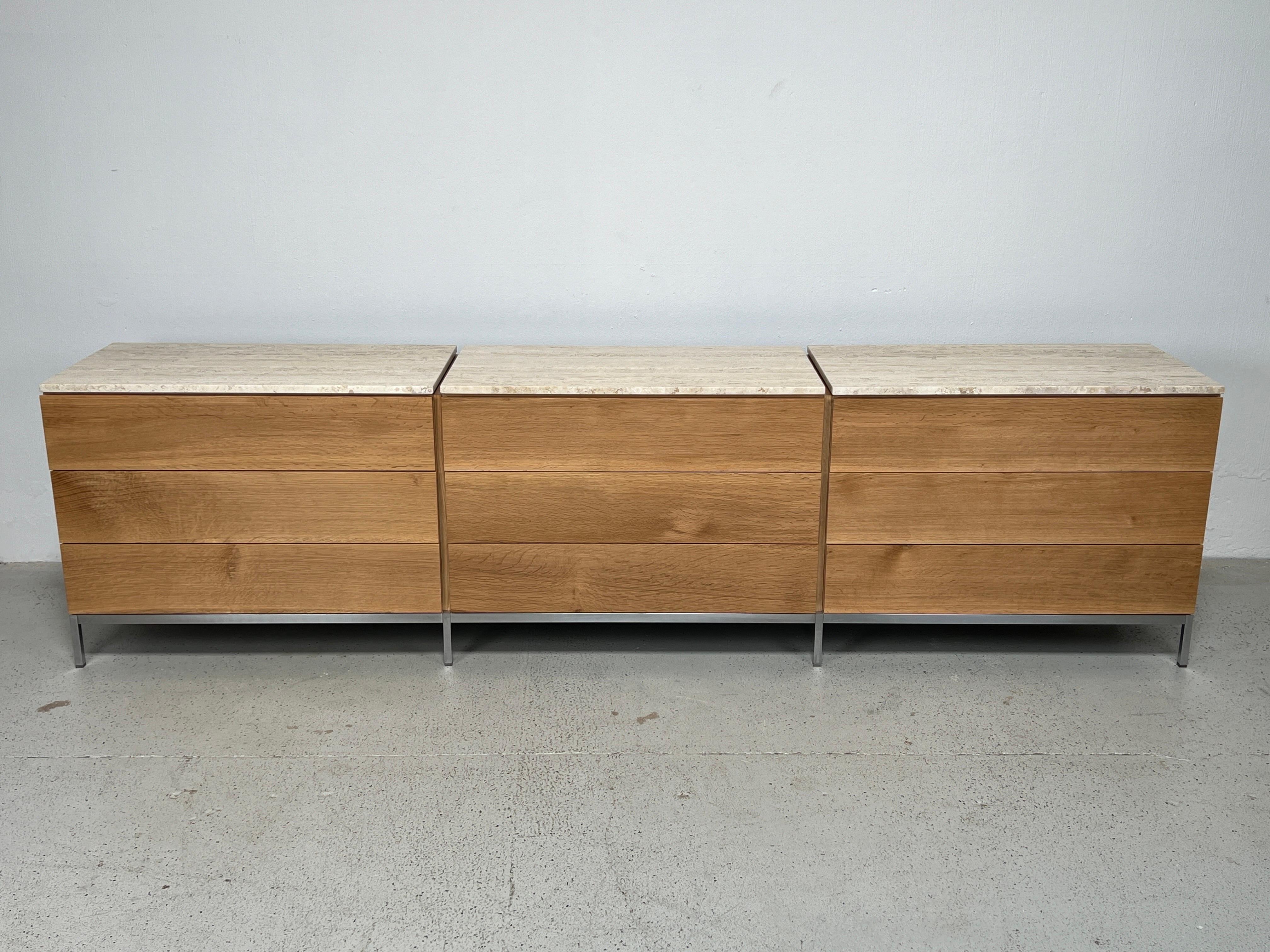 A triple dresser on brushed stainless base in oak with travertine tops. Designed by Florence Knoll for Knoll. 