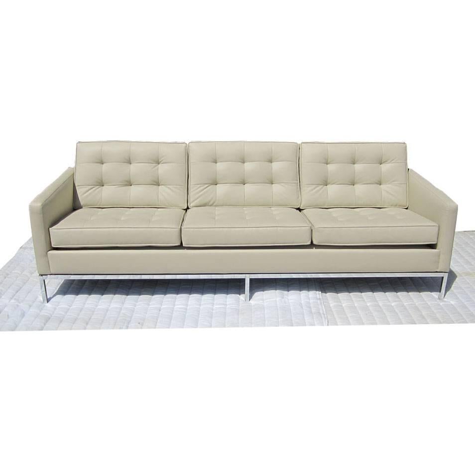 A Mid Century Modern Knoll couch designed by Florence Knoll. This three person sofa features a tufted, off-white ultra leather upholstery and chrome plated steel legs. This classic design is perfect for any modern home.