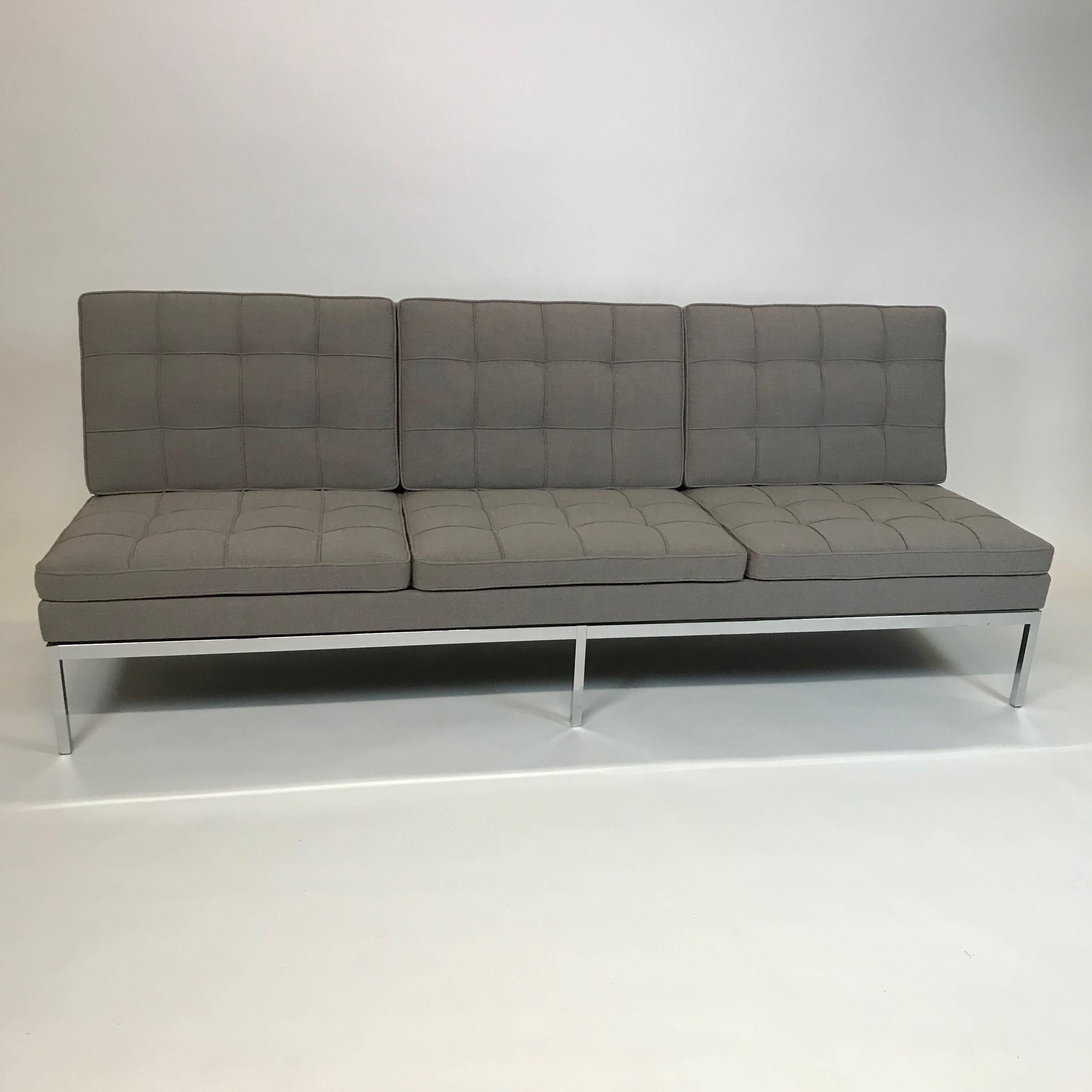 Mid-Century Modern, three-seat, armless sofa by Florence Knoll features a chrome frame with new, box-stitch upholstery in medium gray, cotton linen.