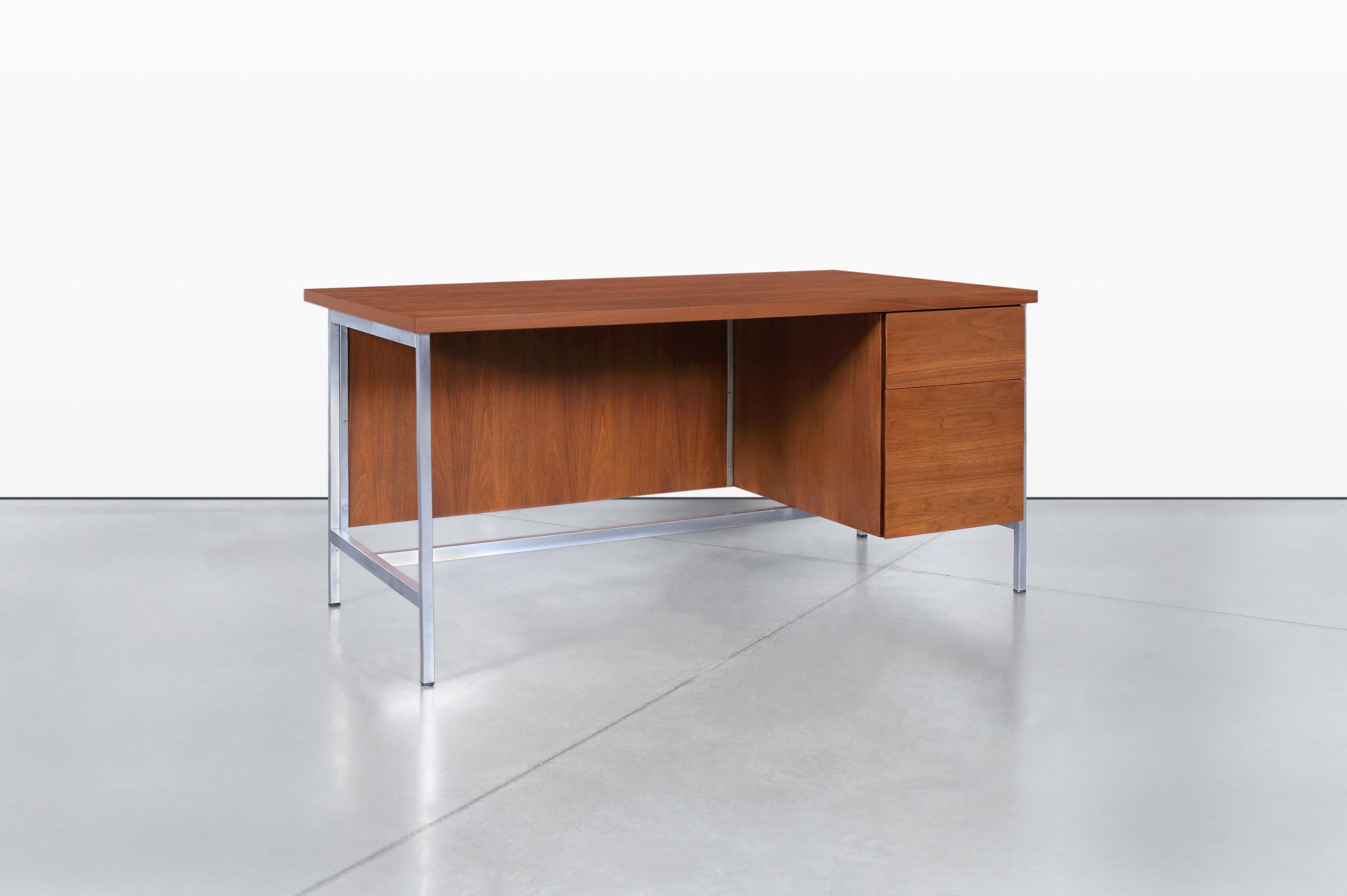 This vintage executive walnut desk, designed by Florence Knoll for Knoll Associates Inc. in the 1950s, is a stunning example of mid-century modern design. Featuring a functional cabinet on the right side with a pull-out drawer and a large file