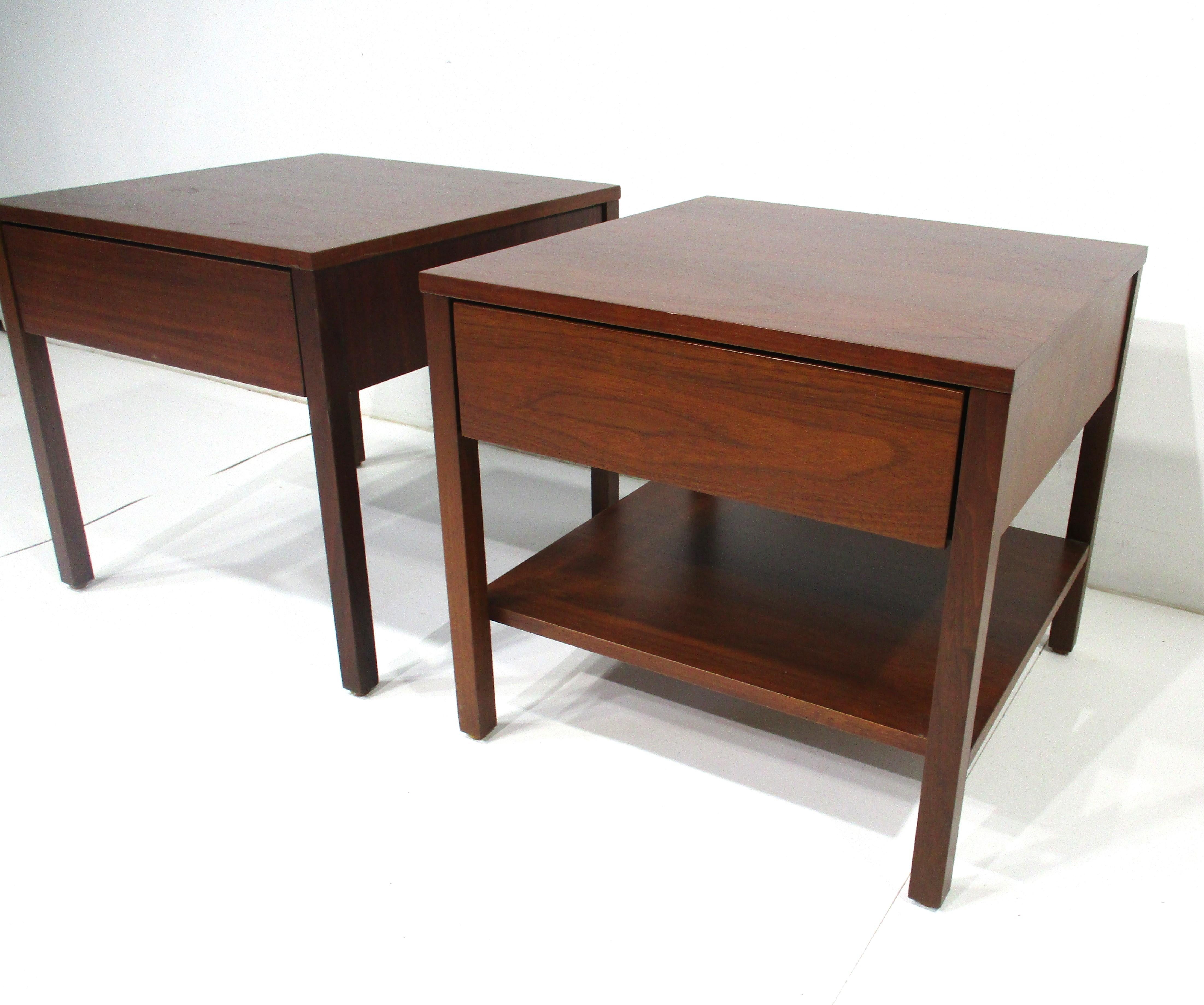 A pair of dark walnut nightstands each having a single drawer and one with a lower shelve . This very well crafted pair of nightstands with a simple but elegant form stays true to the female designers style . Florence Knoll who was head designer and
