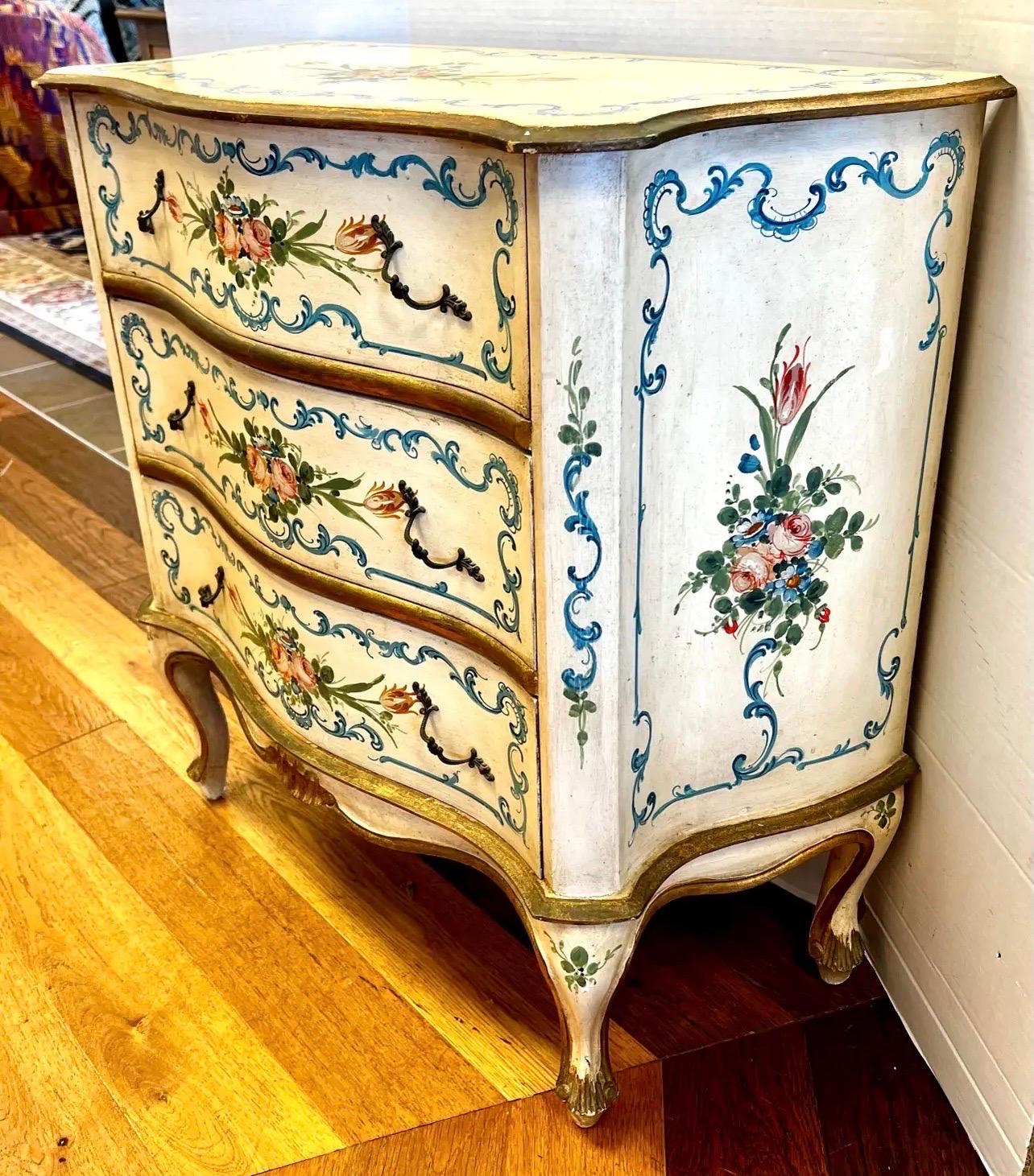 Splendida cassettiera d'epoca Florentia con fronte a serpentina e tre cassetti con motivi dipinti a mano di fiori e volute sul fronte e dettagli dorati.  Prodotto in Italia.