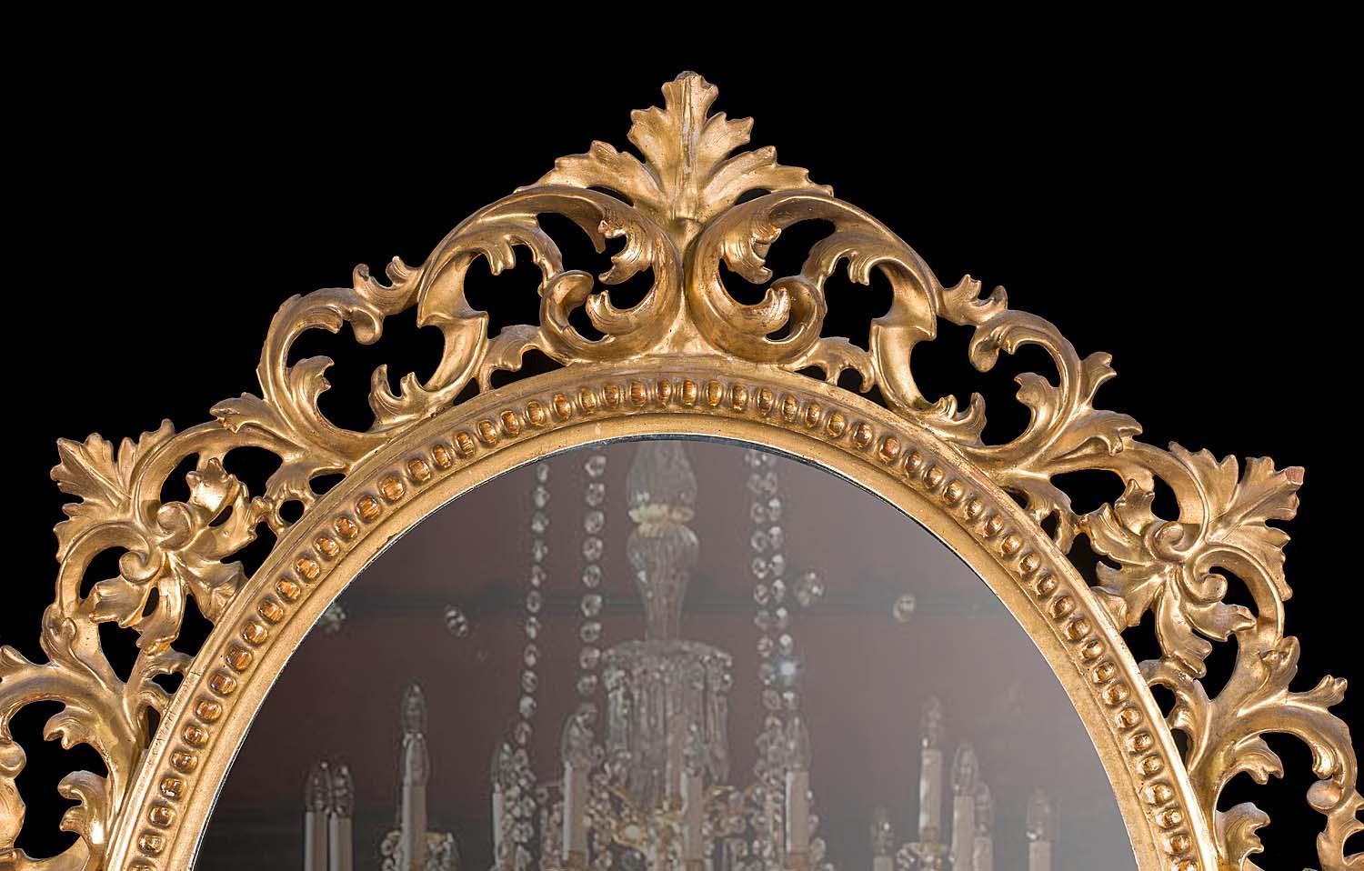 A very pretty gilded oval wall mirror within a beaded and foliate carved frame in the Rococo style. This style of frame is typically of the Florentine frame making workshops, renowned for the quality of their carving. Florentine, late 19th century.
