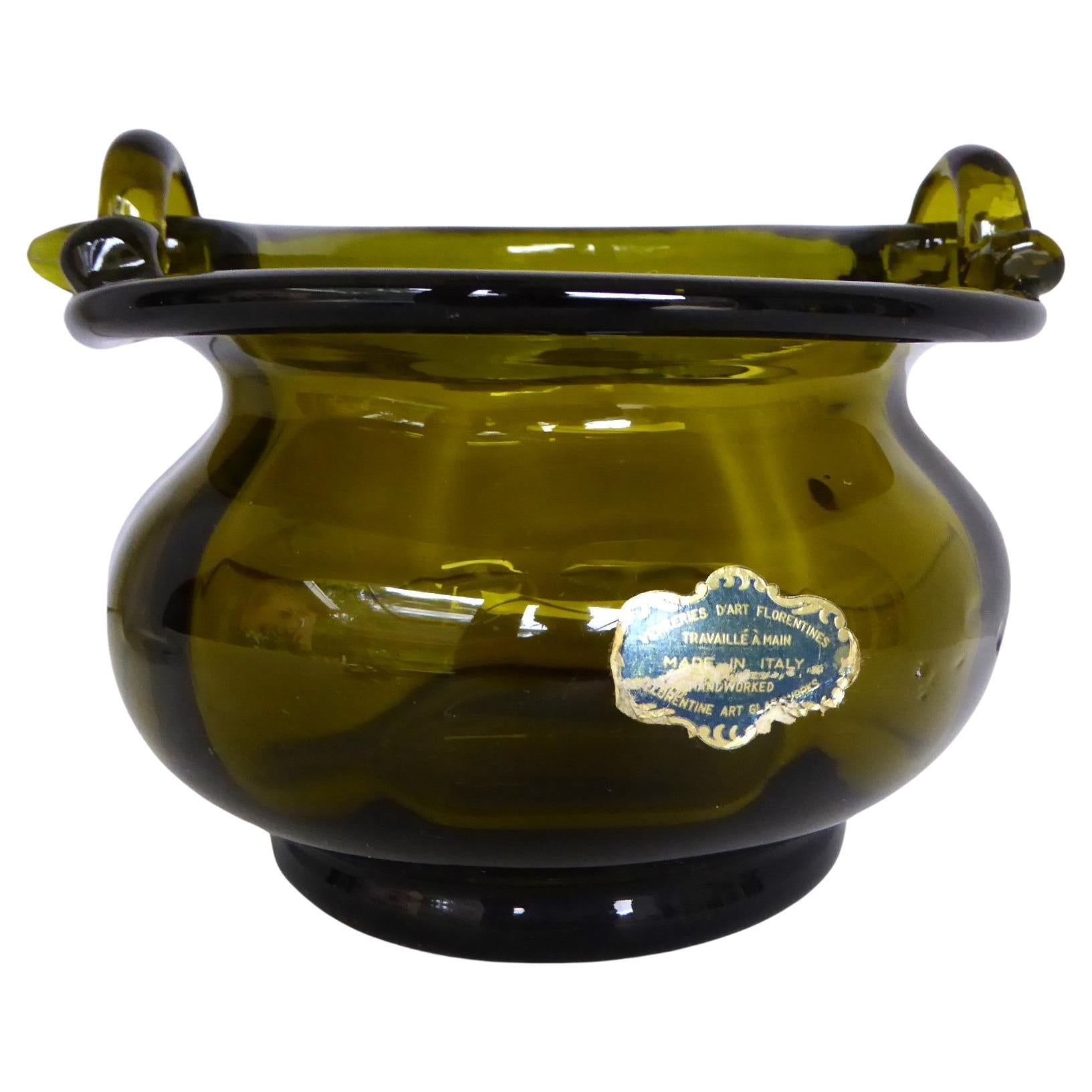 Italian Mid Century hand-made olive Green glass basket with handle made by Florentine Art Glassworks in the 1960s.  The vessel has an undulating body and the handle is secured by 2 glass holders on the rim of the body.   Please note, the handle does