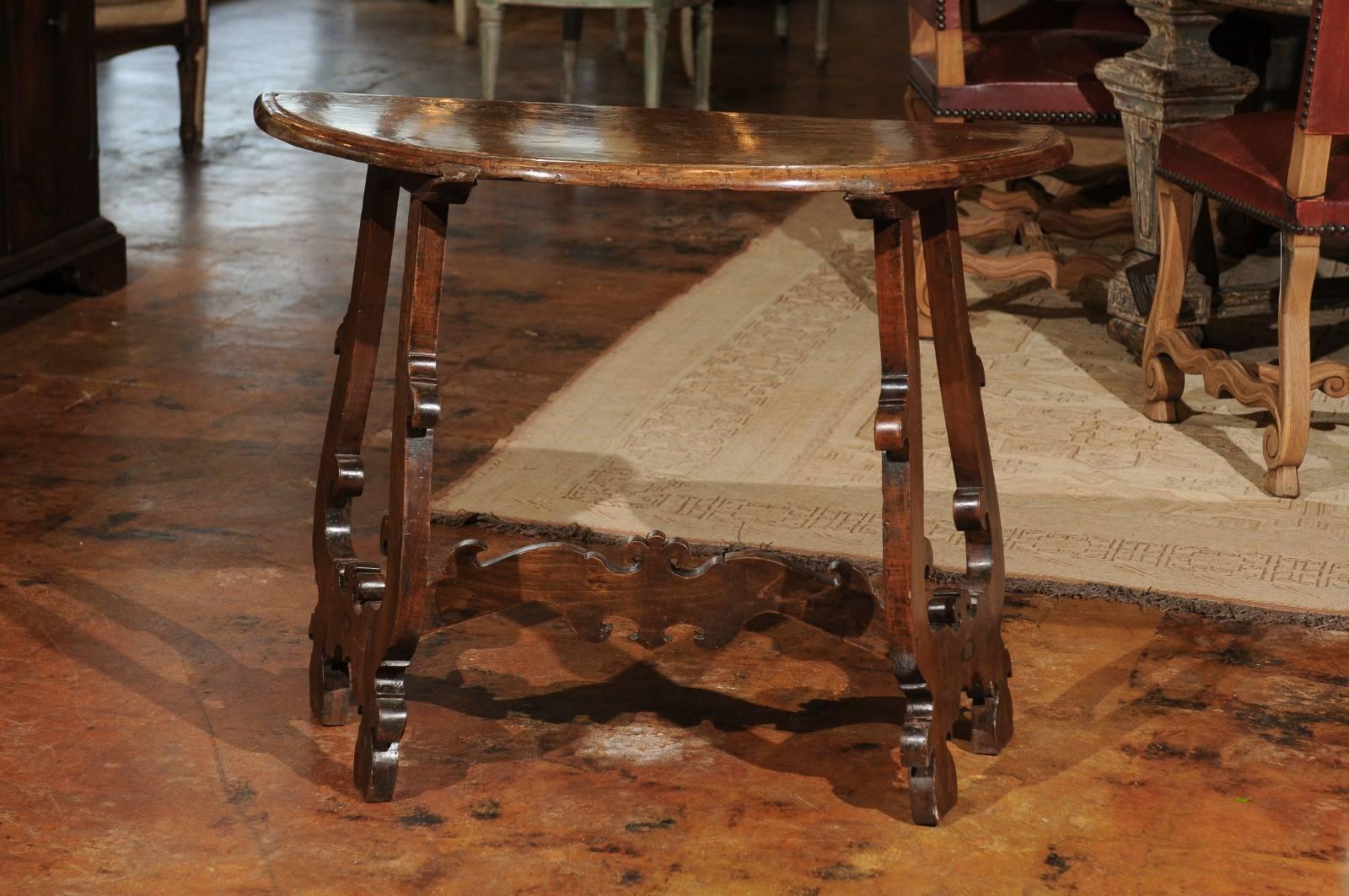 An Italian Baroque Revival carved walnut demilune console table from Florence with lyre-shaped legs and cross stretcher from the late 19th century. Born in Tuscany during the 1880s, this demilune table feature a semi-circular top with rounded edges,