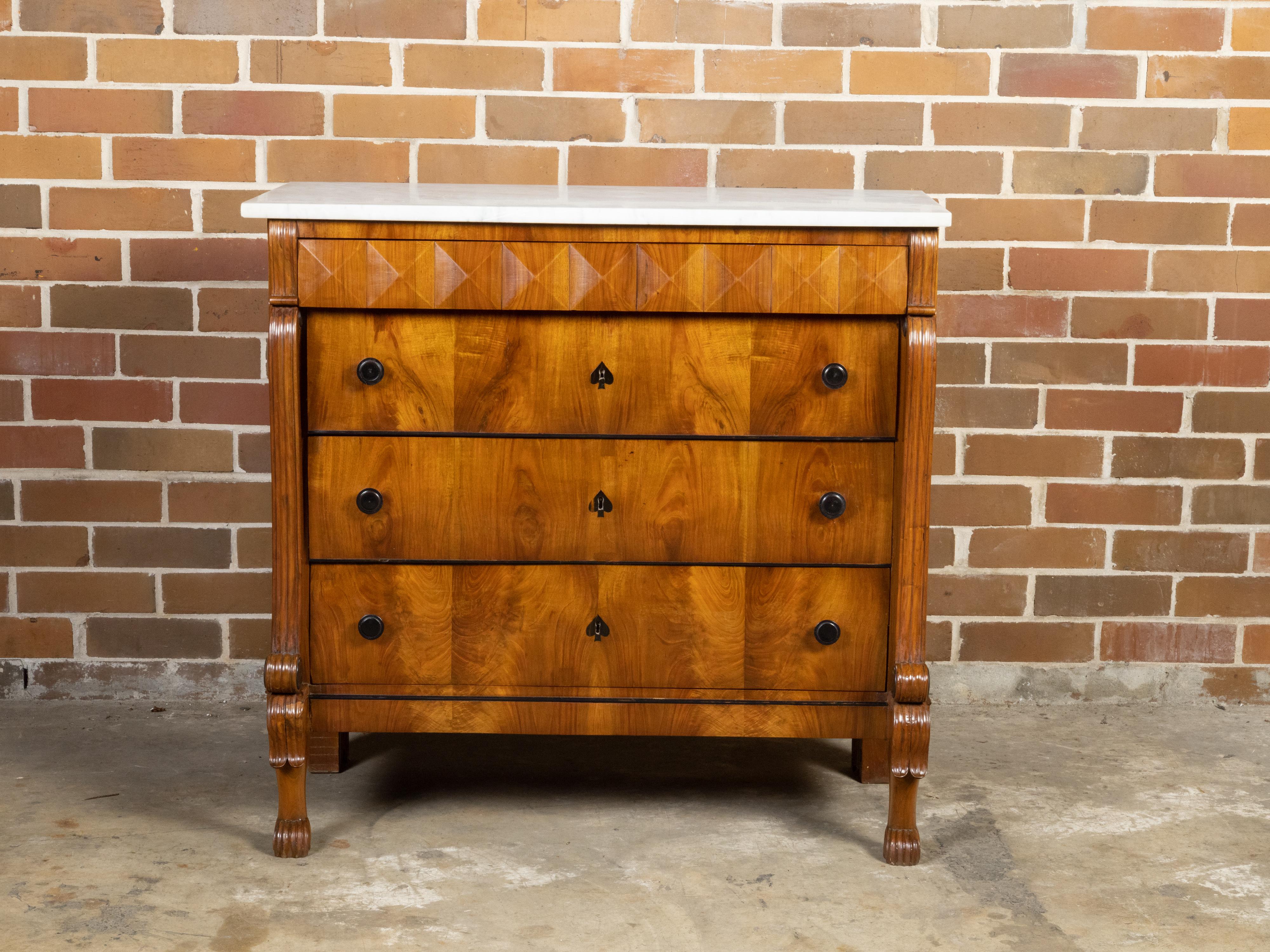 An Italian Florentine wooden commode from the 19th century, with white marble top, three drawers, volutes, paw feet and ebonized accents. Created in Florence during the 19th century, this commode features a rectangular white marble top sitting above