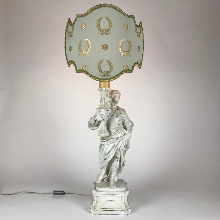 Lampe de table de style baroque en forme d'angelot par Chelini Firenze Manifacture, une grande lampe de table italienne de la fin du 20e siècle présentant une figure sculptée d'ange debout avec une finition ultérieure peinte en blanc.

L'abat-jour