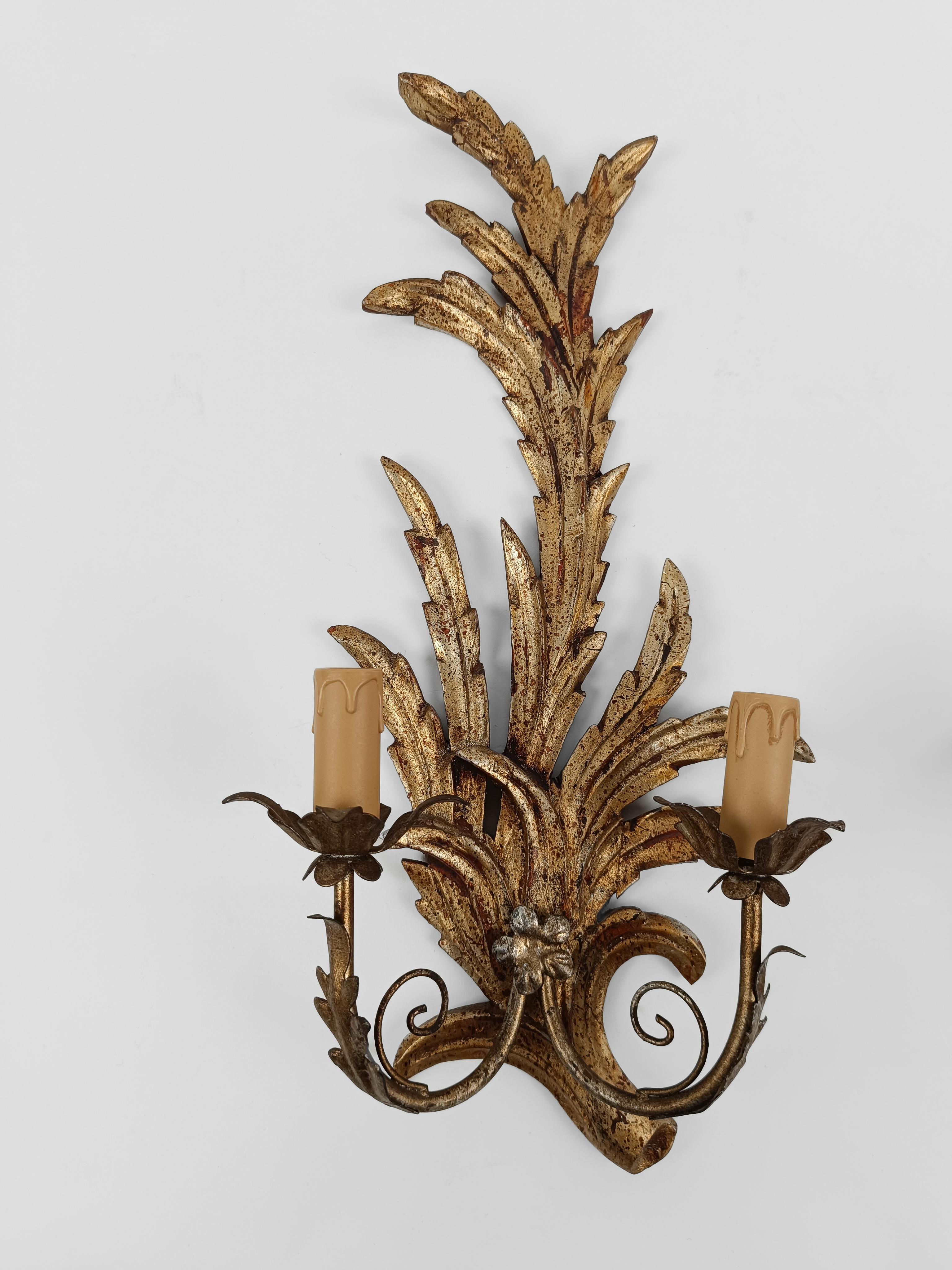 A pair of sconces made in Italy during the mid 20th century but in the Rococo style.

The hand-carved lime wood structure with foliate motifs is gilded with the ancient gold leaf technique.

serrated leaves reminiscent of palm leaves that transform