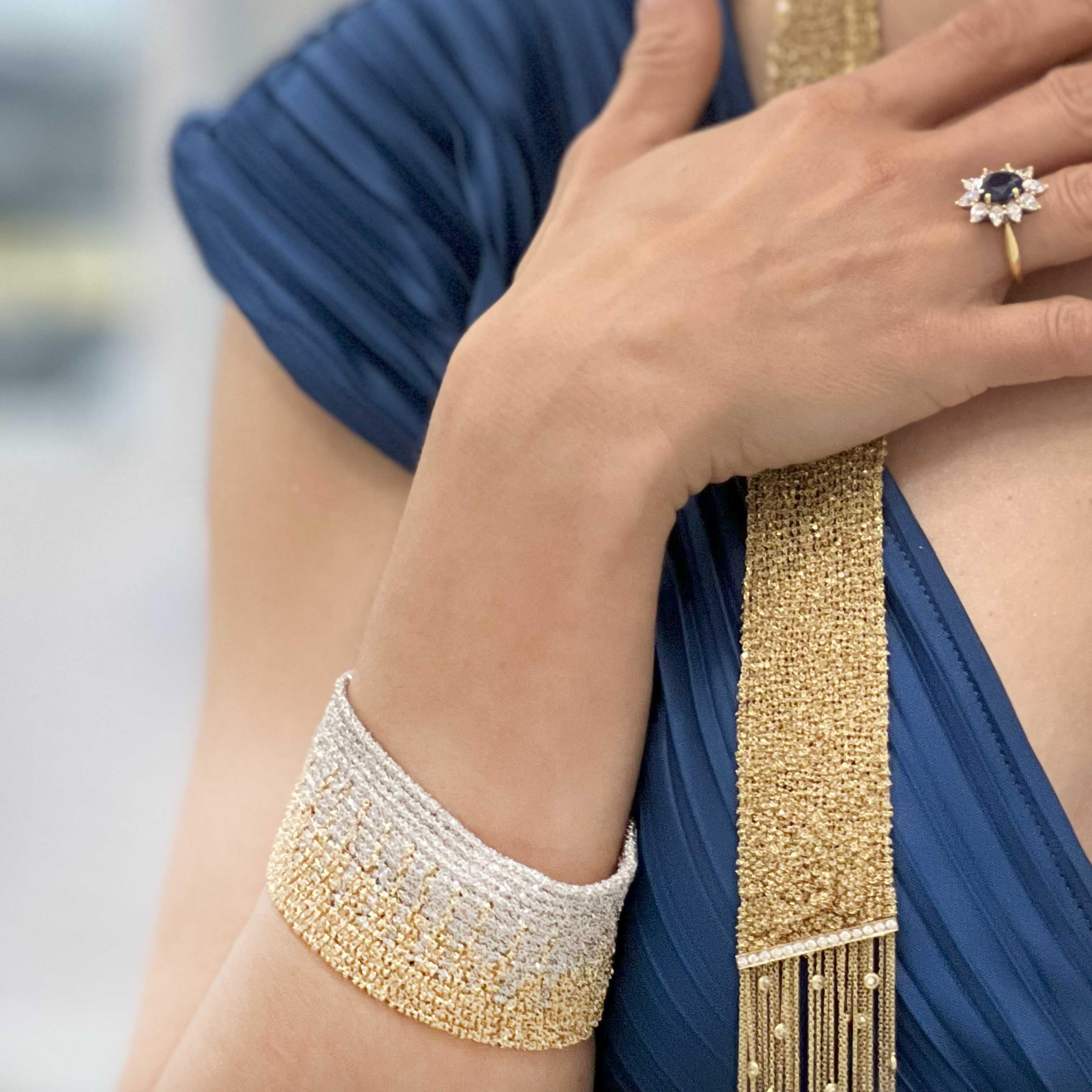 Esta pulsera de oro de 18 quilates bicolor tejida en telar florentino pesa 109,5 gramos, mide 7,5 pulgadas de largo y 1,5 pulgadas de ancho, es una pieza de joyería lujosa e intrincadamente elaborada. Aquí tienes una descripción detallada:

Material