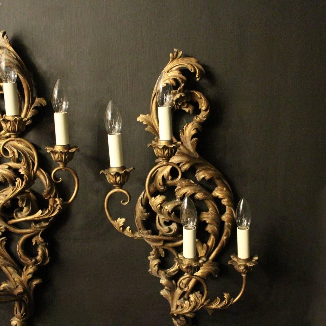 A decorative Italian carved silvered giltwood and toleware opposing four arm antique wall lights, the double tiered foliated toleware leaf scrolling arms with wooden bulbous leaf candle sconces, issuing from an ornate pierced Acanthus leaf silvered