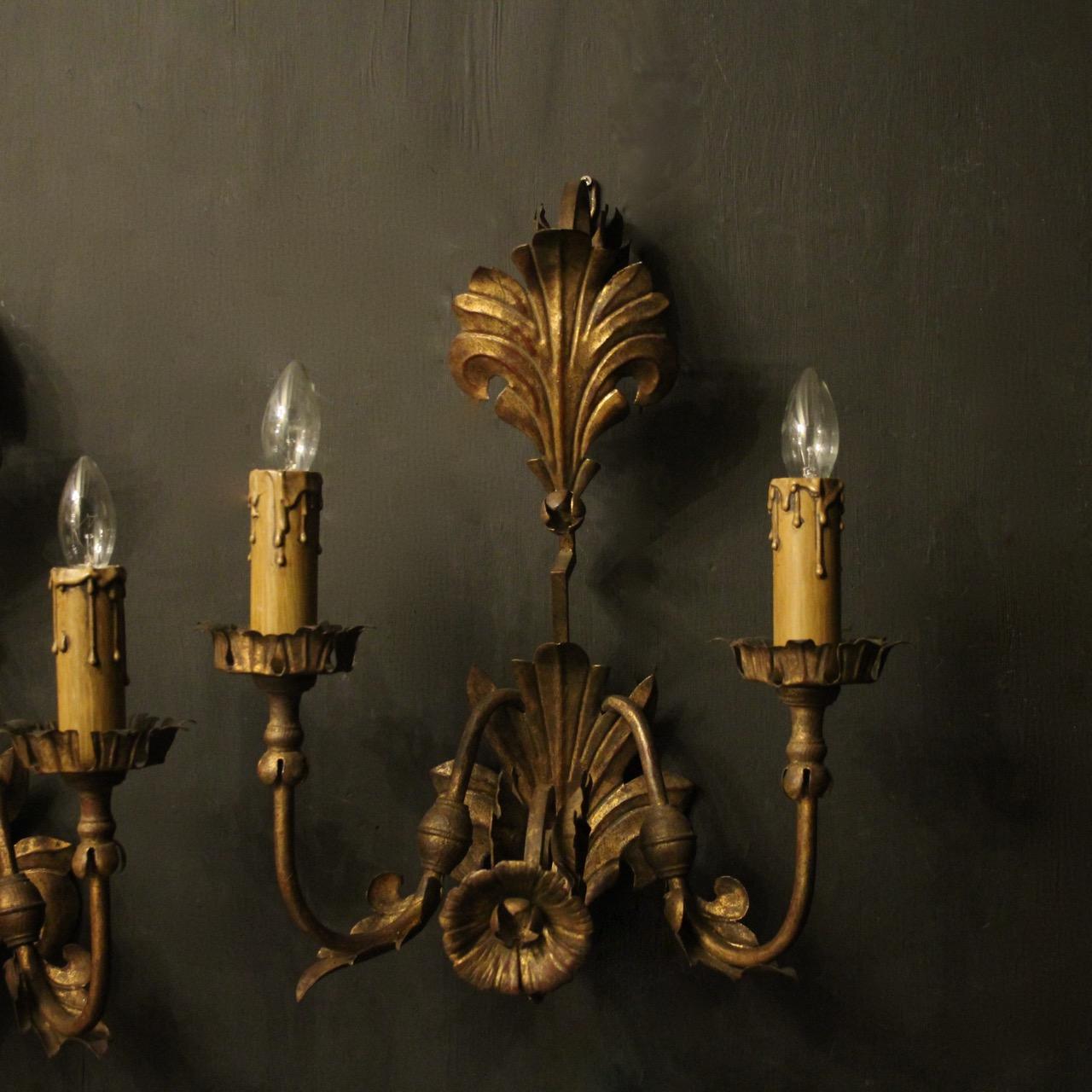 A large decorative Italian Florentine pair of gilded twin arm antique wall lights, the ornate metal Acanthus leaf scrolling arms with circular leaf bobeche drip pans, issuing from a lovely foliated elonagated backplate with large leaf finial,