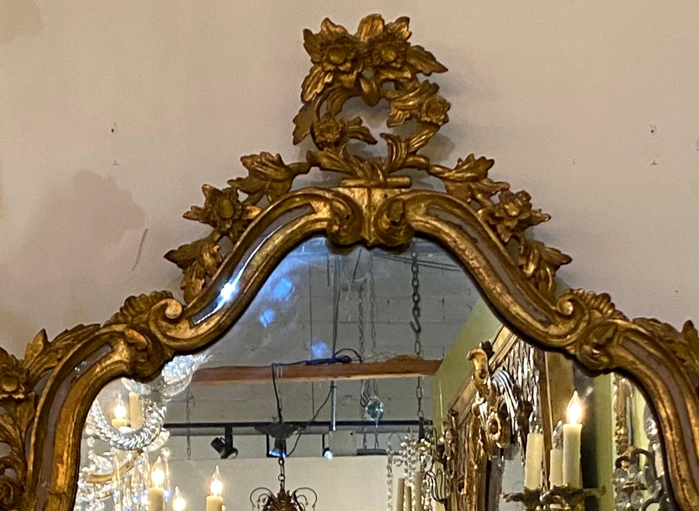 Florentine giltwood wall mirror, 20th century, the center flat mirror plate surrounded by additional rows of mirror plates, having rocaille and foliate carved frame.